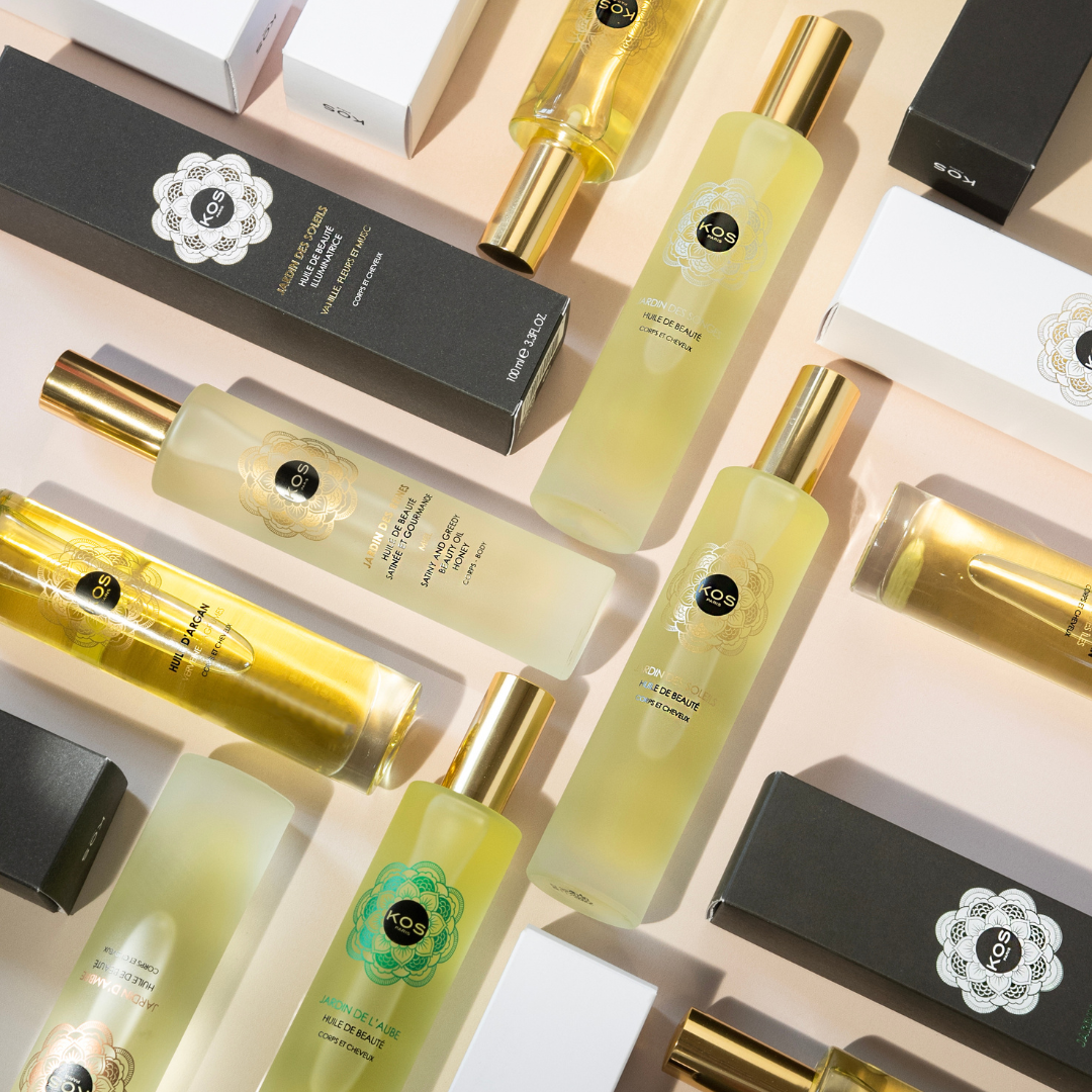 Arranged bottles and boxes of beauty and hair care products with black, white, and gold packaging on a light pink surface.