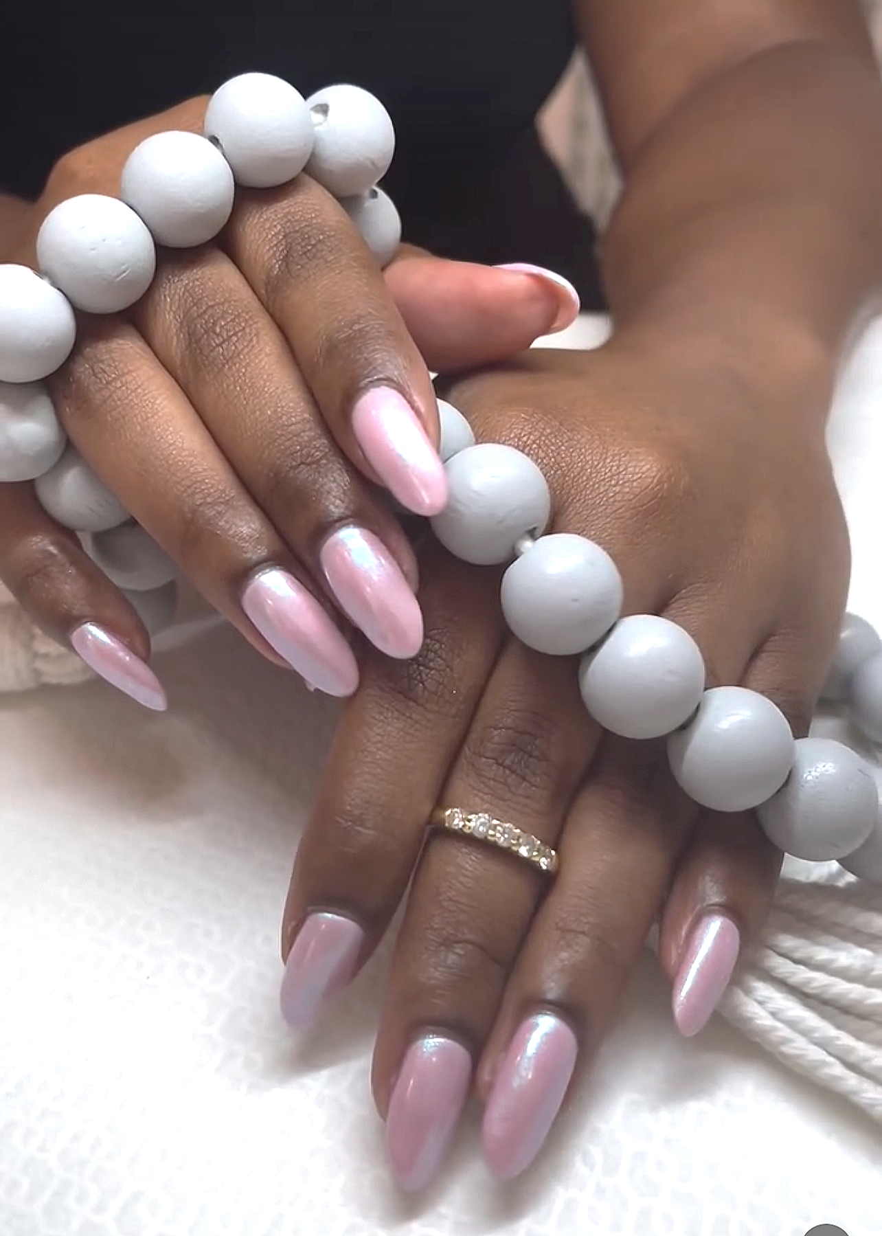 Close-up of a woman's hands and feet with manicured nails and a wedding ring, surrounded by white lilies.