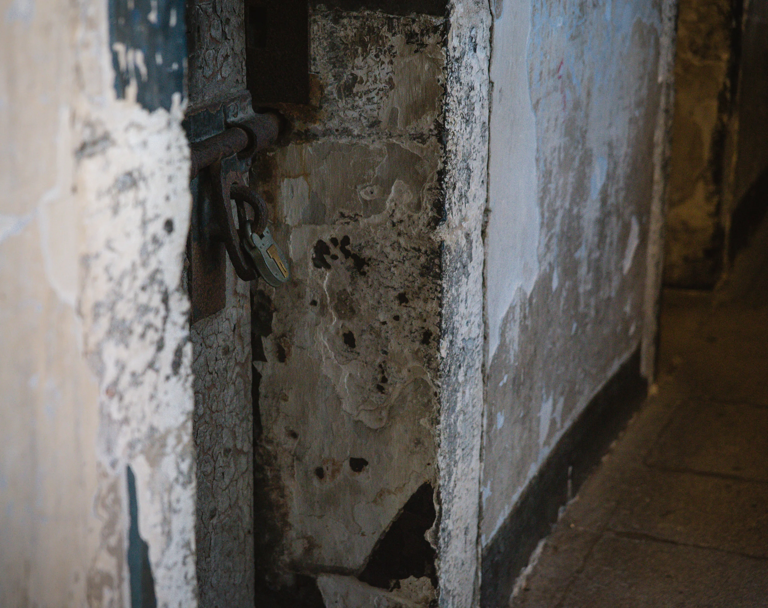 A lock rests on the door of one of the cells. 