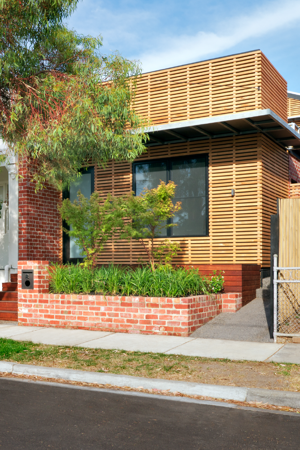 sustainable terrace house in brunswick west melbourne with timber batten cladding and a recycled red brick planter
