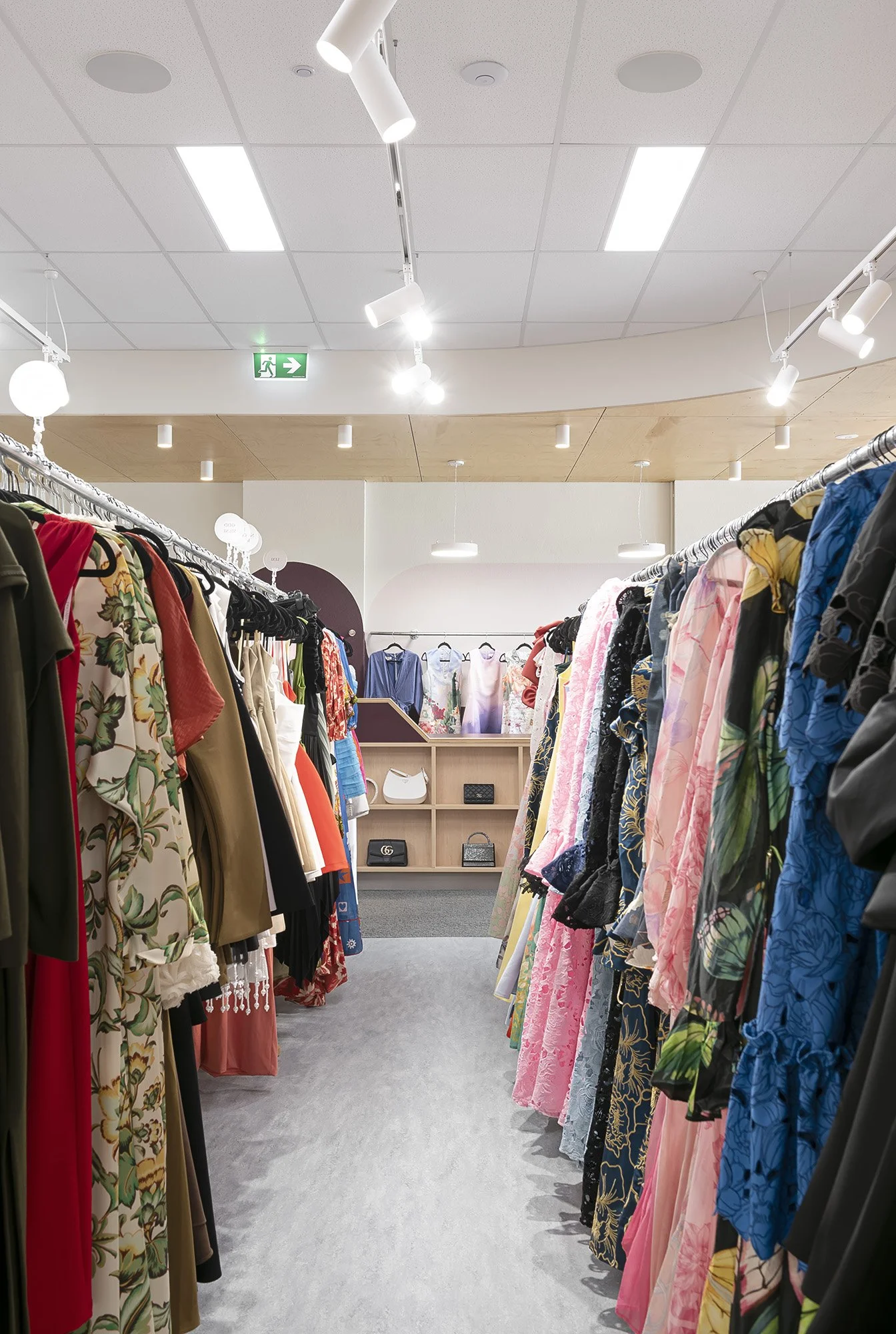 View along a dress rail toward the reception desk and built-in accessory shelving