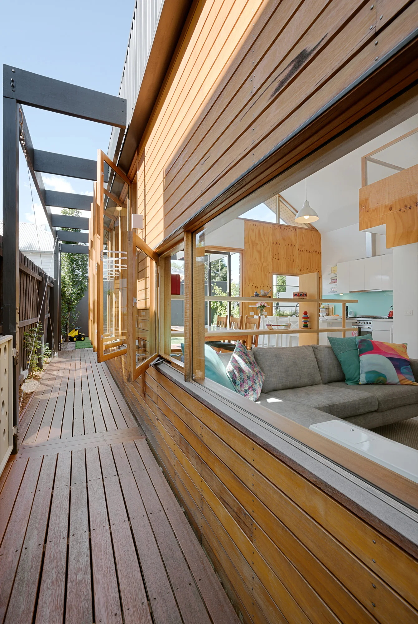 Timber-clad side elevation with a row of open awning windows drawing cross-breezes through the living space