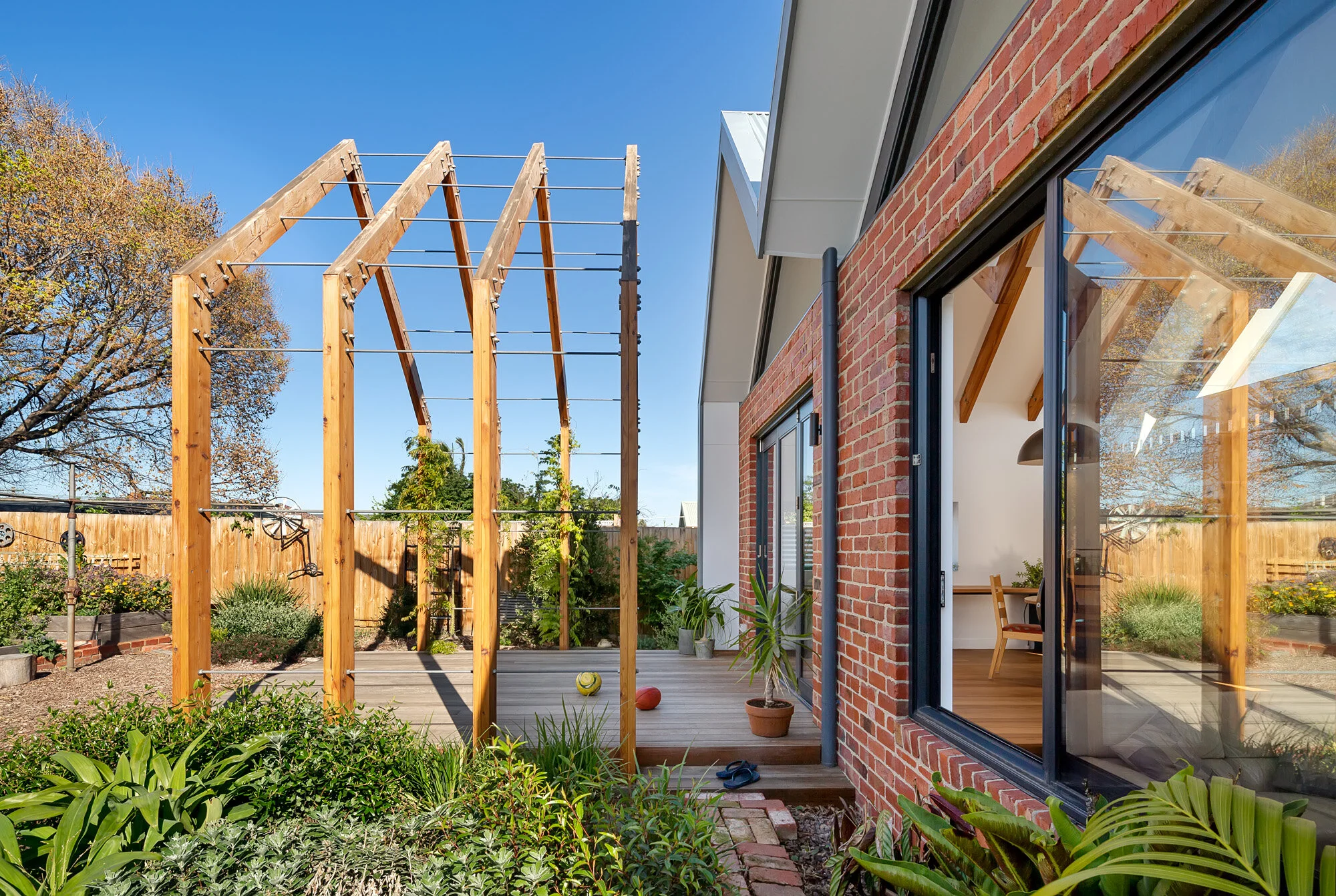Side view of the timber pergola's wire trellis for climbing vines, beside the brick extension's glazed gable end