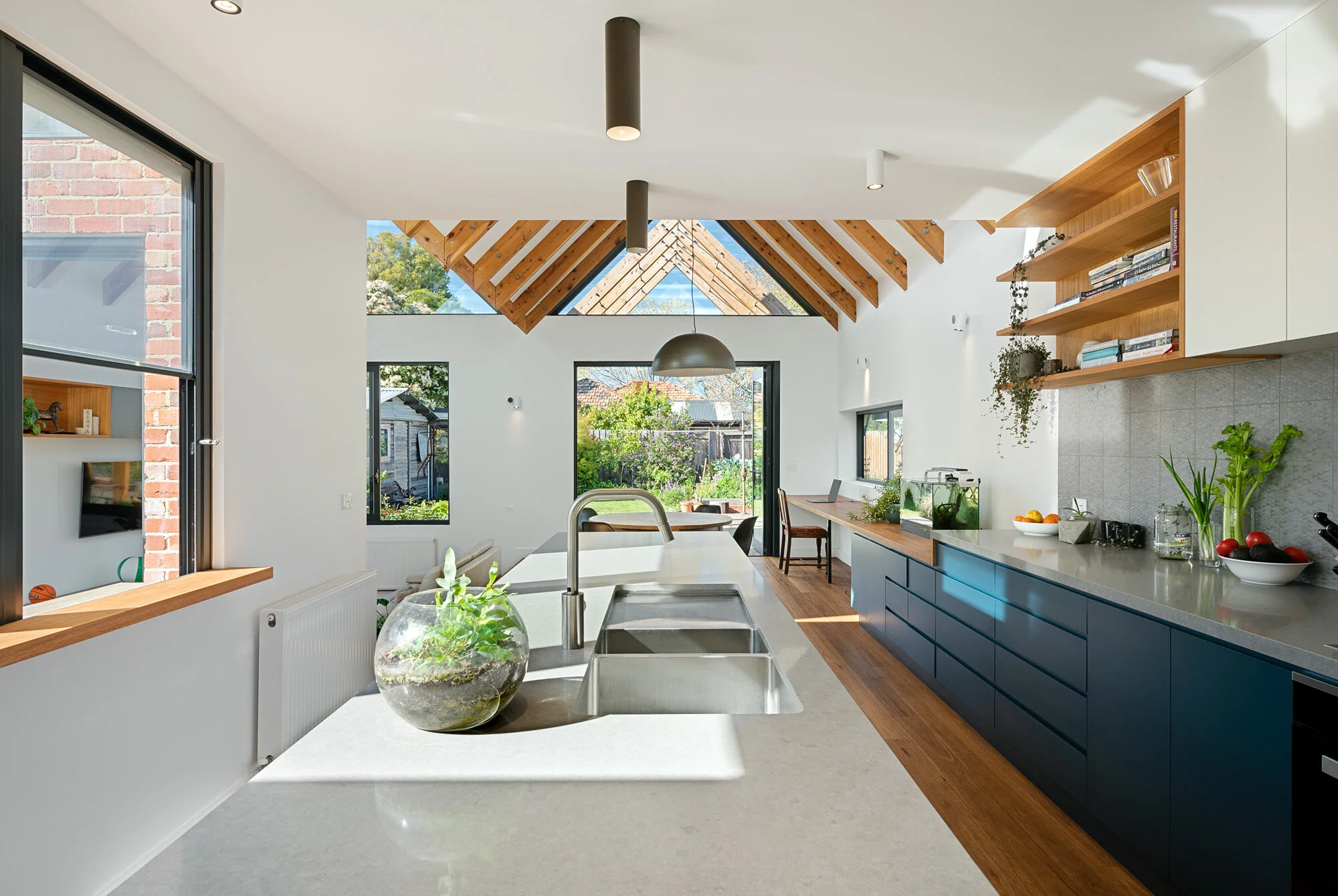 Kitchen island bench opposite a servery window with views to garden beyond.