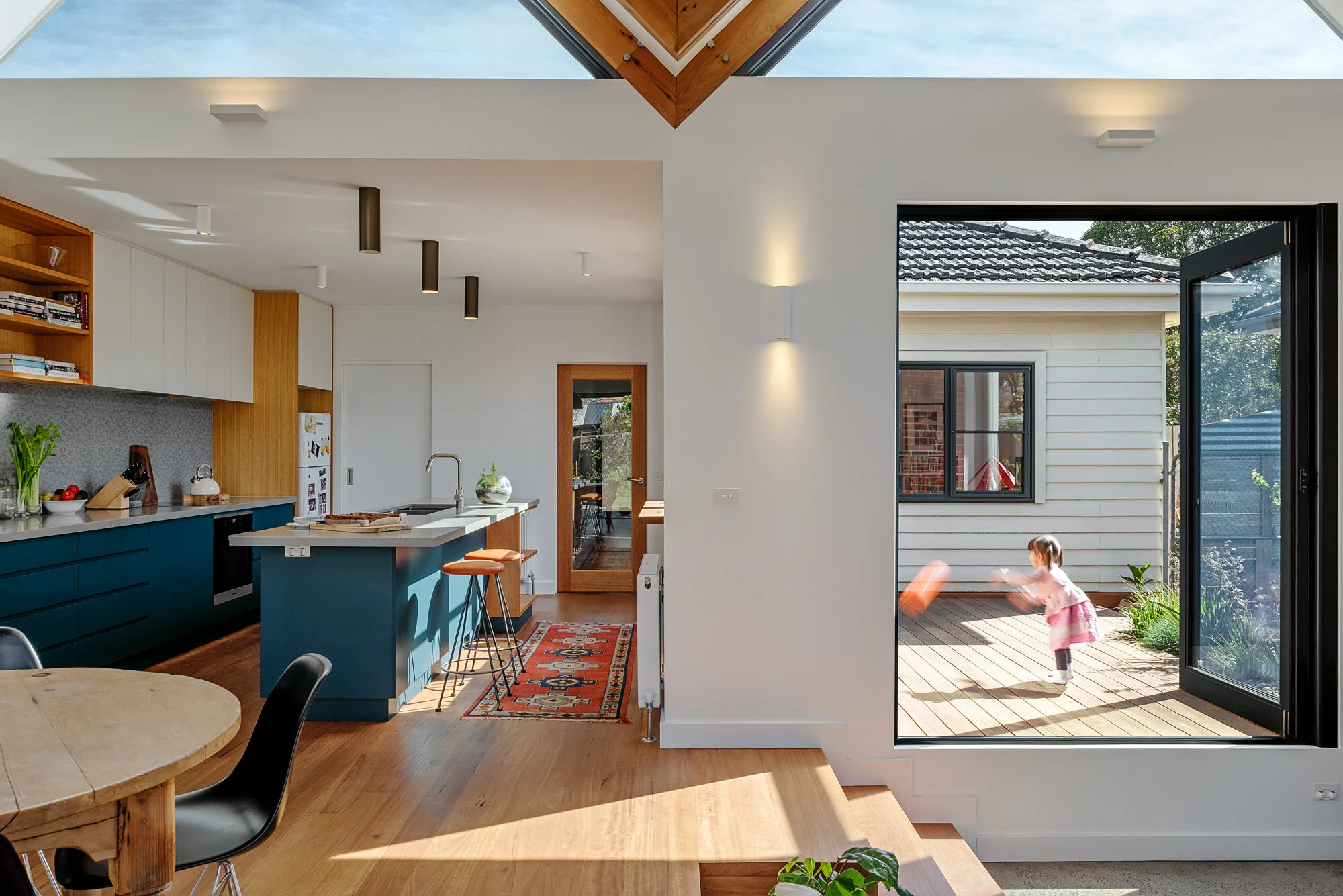 Open-plan kitchen and living space stepping down to a sunken nook, with glazed doors opening onto the deck