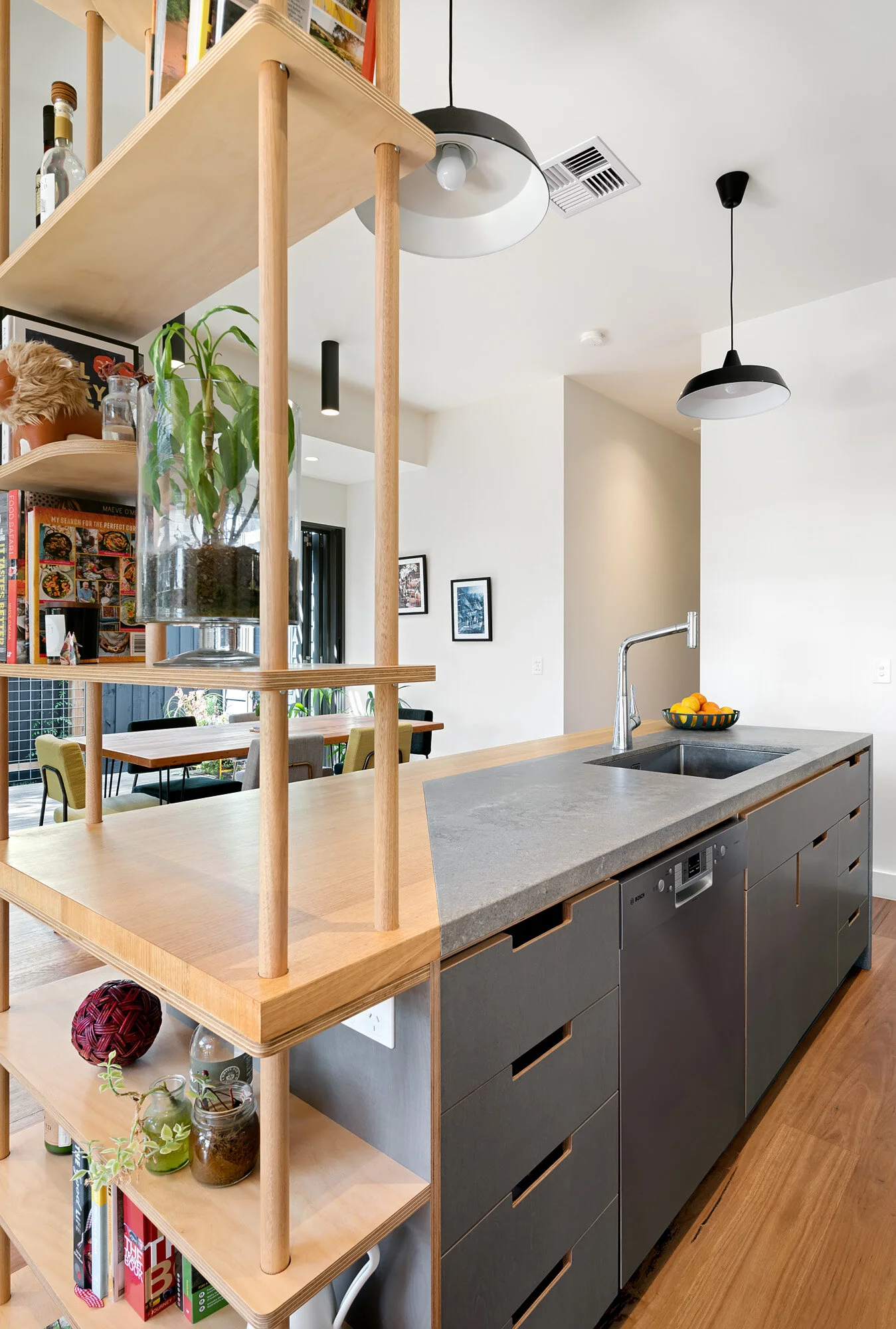 Kitchen island detail with a concrete benchtop, plywood joinery and open timber shelving
