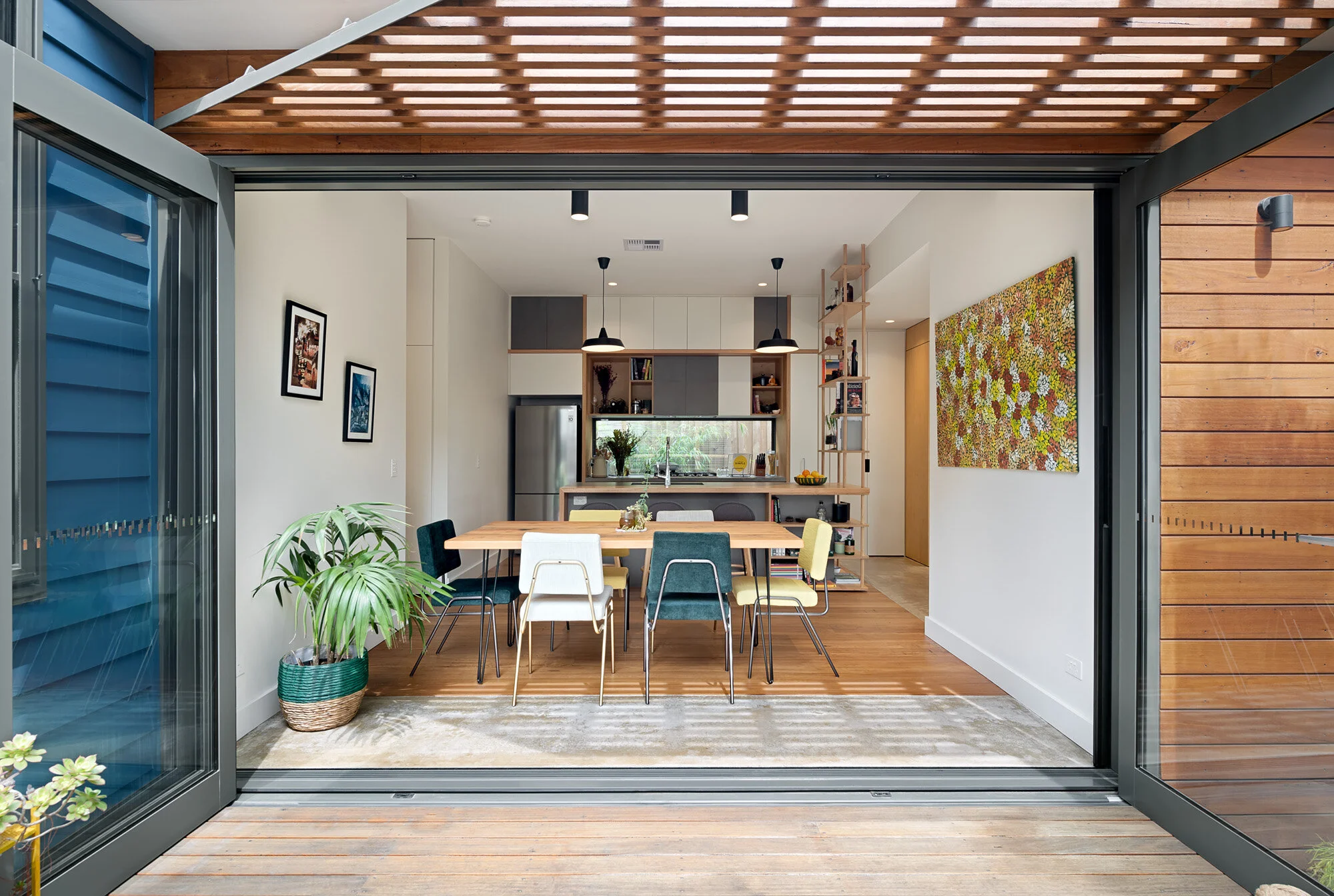 Passive solar indoor outdoor living with deck and slatted shade screen over