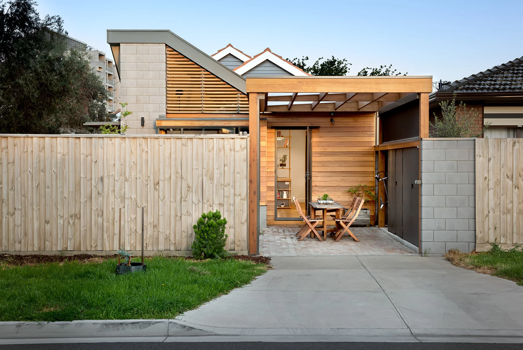 Carport doubles as outdoor seated area with compact storage. Shiplap clad walls