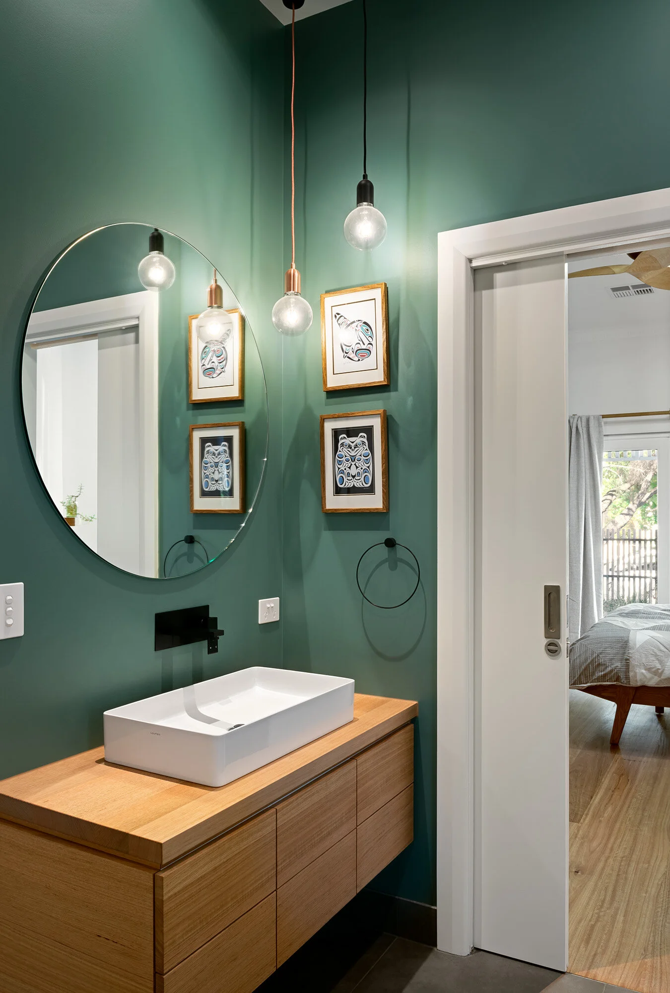 Colourful bathroom with custom timber joinery and round mirror