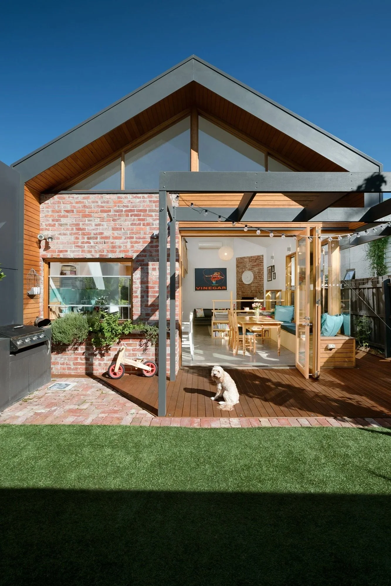 Gable-roofed rear extension in brick and timber, with a pergola deck, herb planter and vegetable garden bed