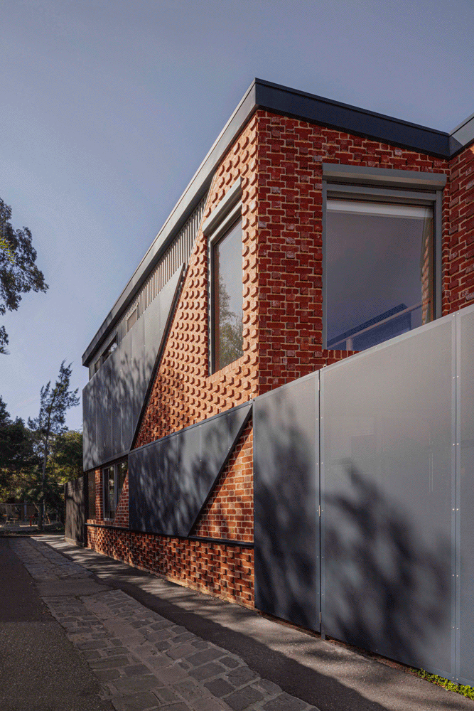 Close view of the operable perforated privacy screen being opened against the recycled brick laneway facade