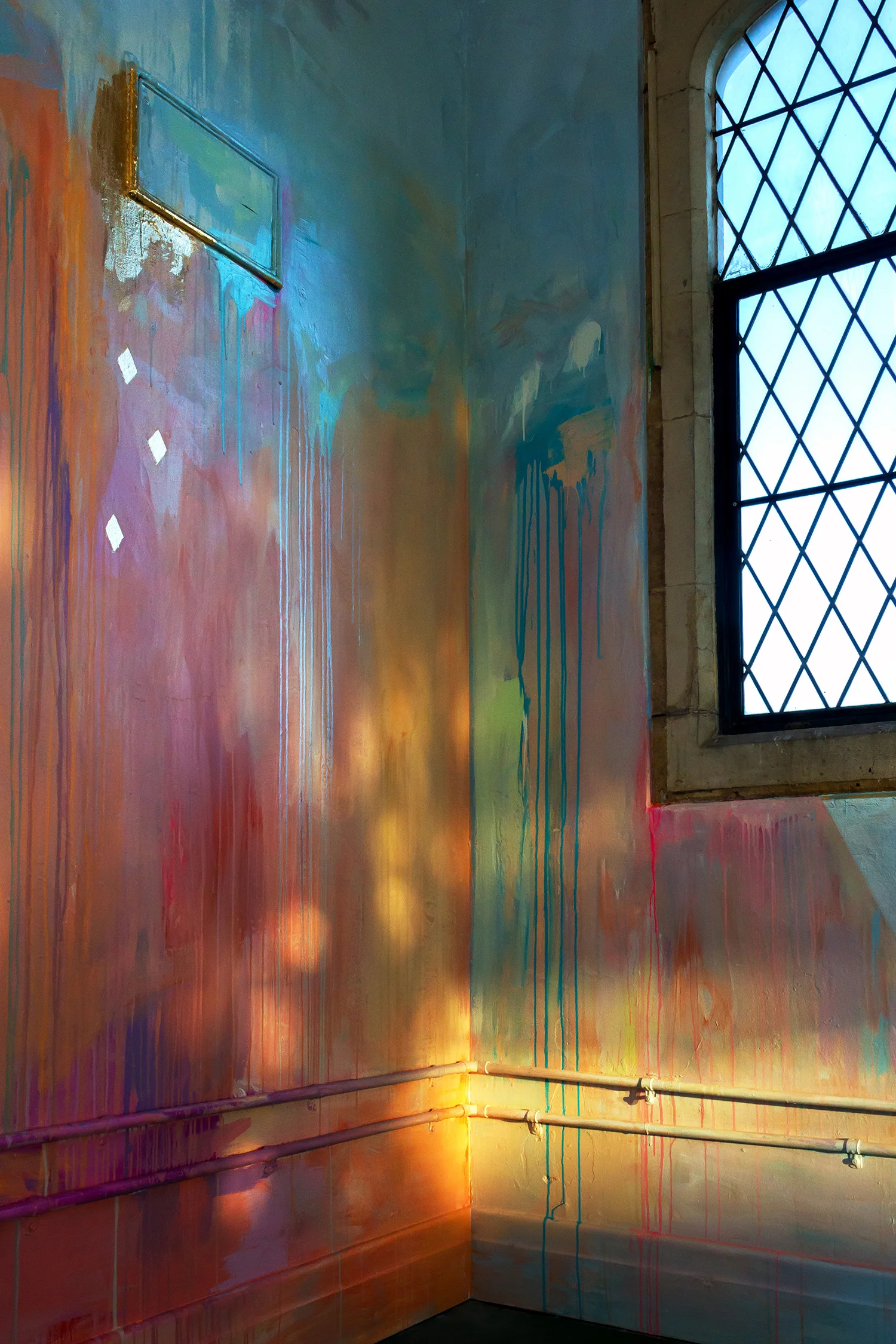 Large scale abstract mural with rainbow stripes in warehouse like tower, features gold leaf metallic birds flying out of the window, round arch windows, pillars and concrete floor, reflections of light looks like fire and fairy lights.