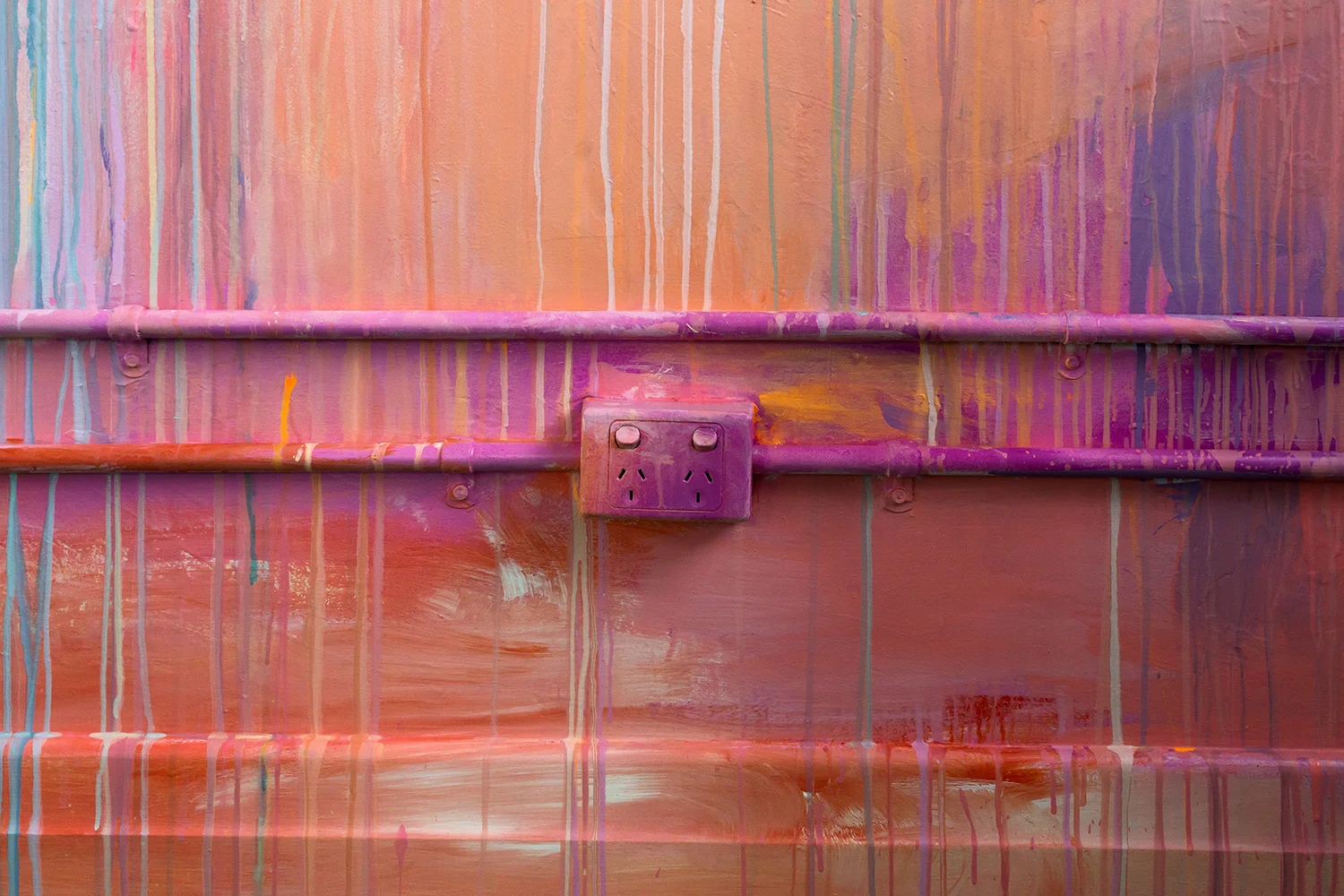 Close up power socket, part of larger abstract painted mural, brush strokes and drips of bright energetic color are featured.