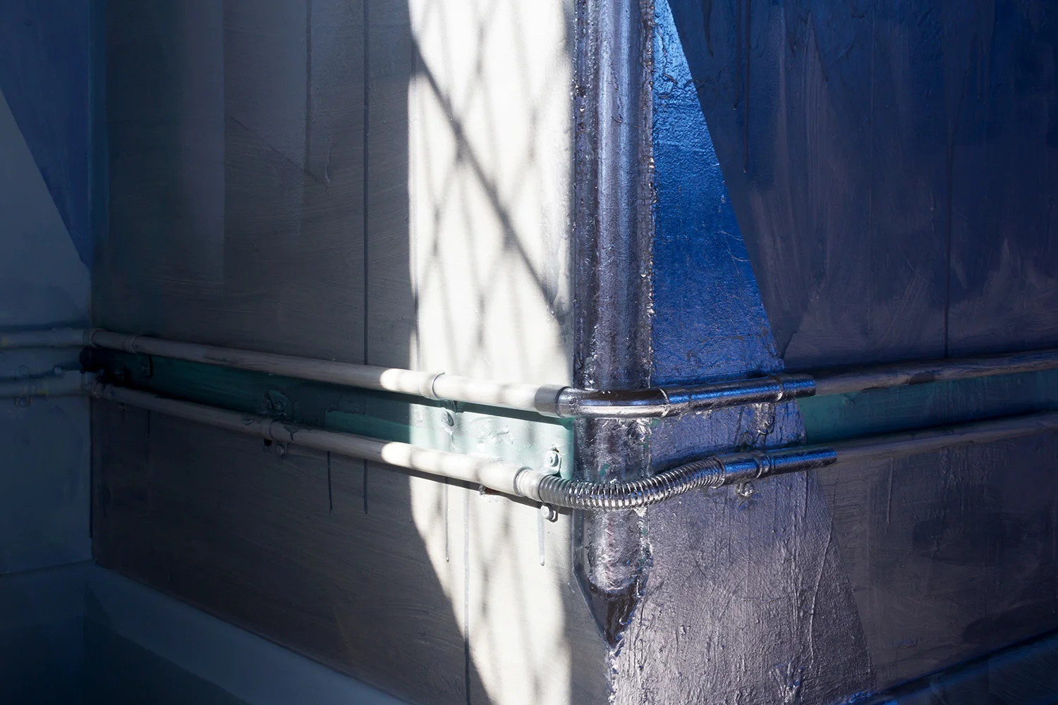 Detail of abstract contemporary painting, part of a large scale mural painted in a warehouse like tower, features geometric silver leaf shapes and metallic silver paint reflecting light.