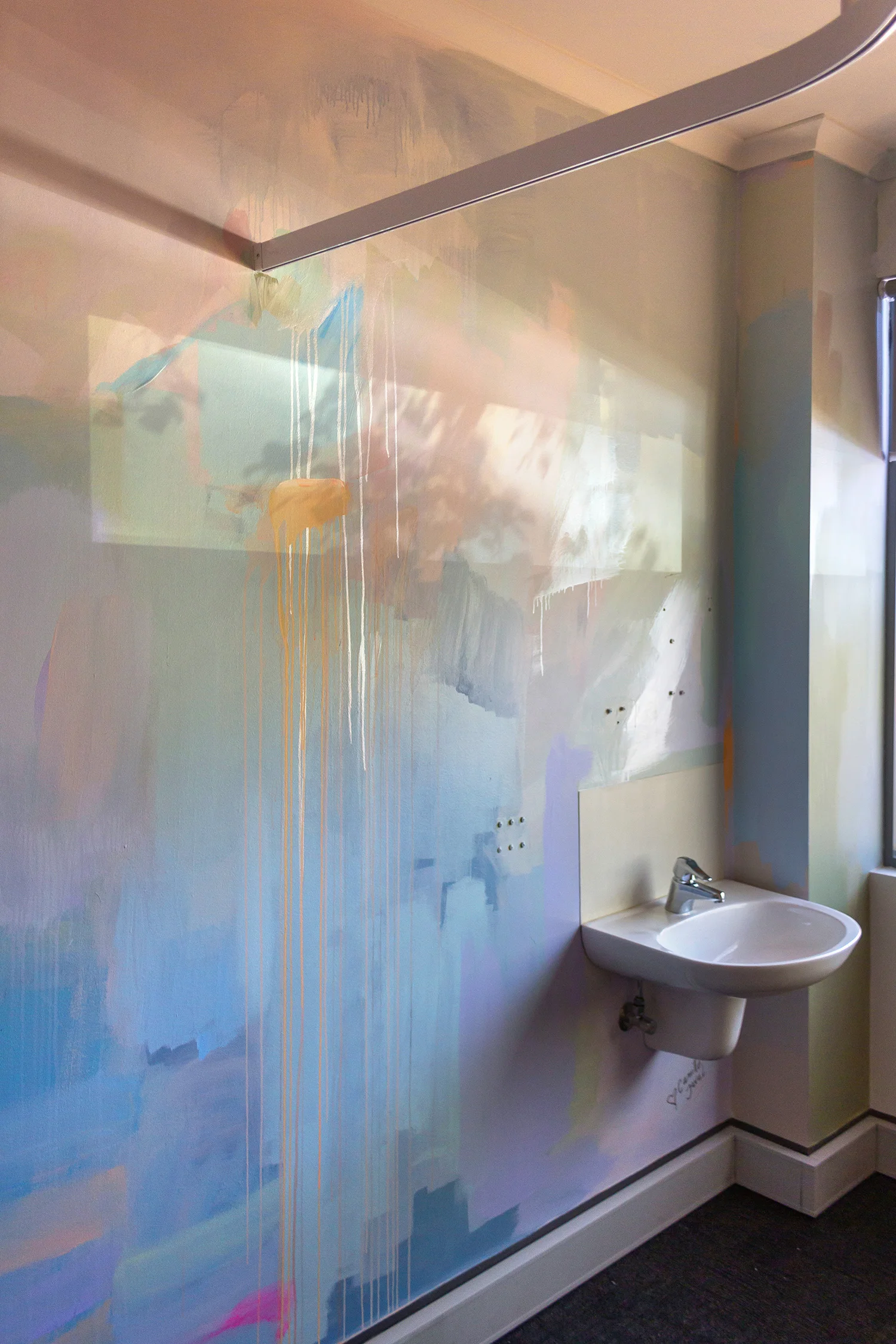Pastel abstract mural painted in an OB/GYN office, shadows from the nearby window project tree leaves onto the wall.