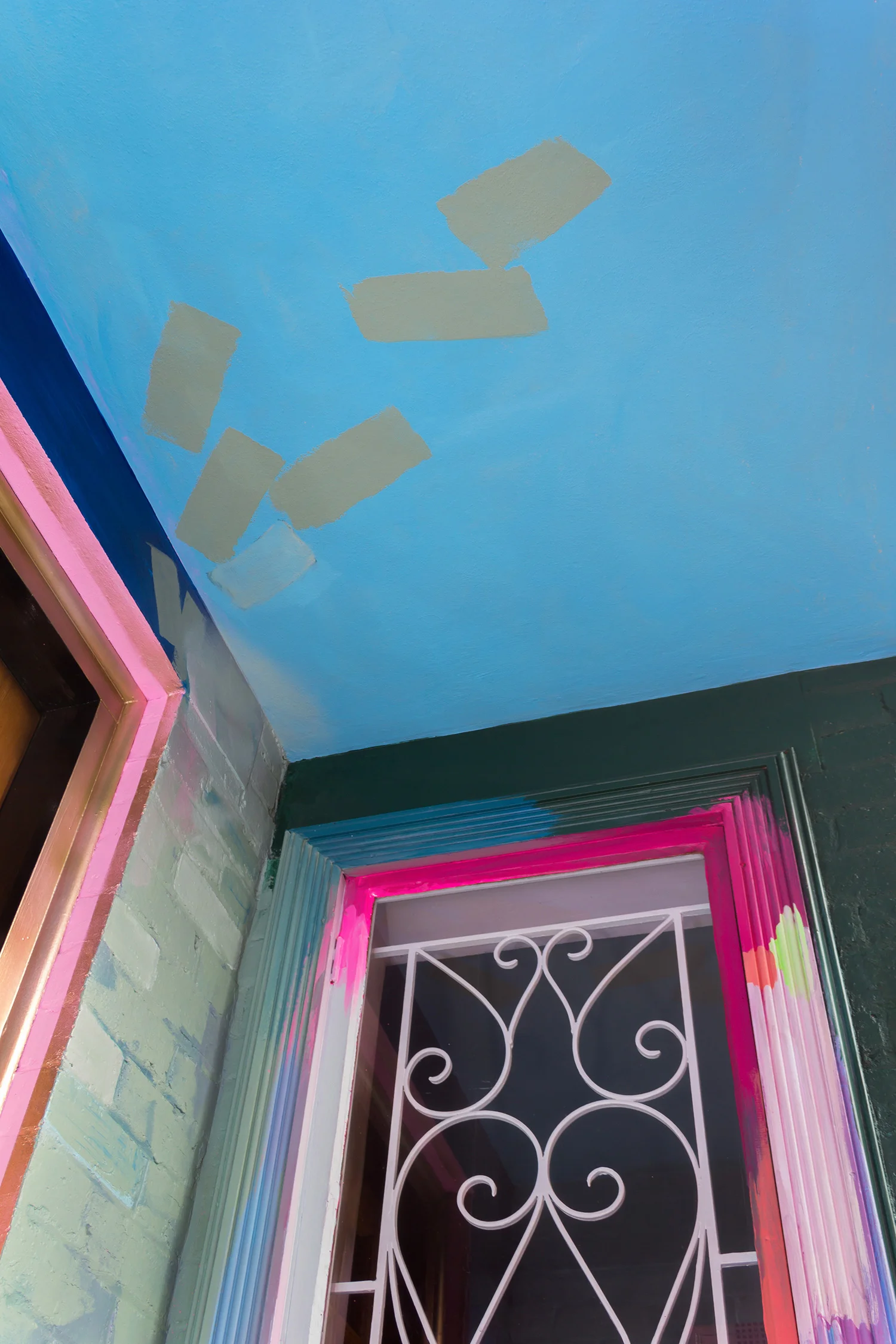 A residential home has been used as a giant art canvas, with a vibrant, abstract design painted on the bricks and window frames. The painted marks move across the walls and along the ceiling.