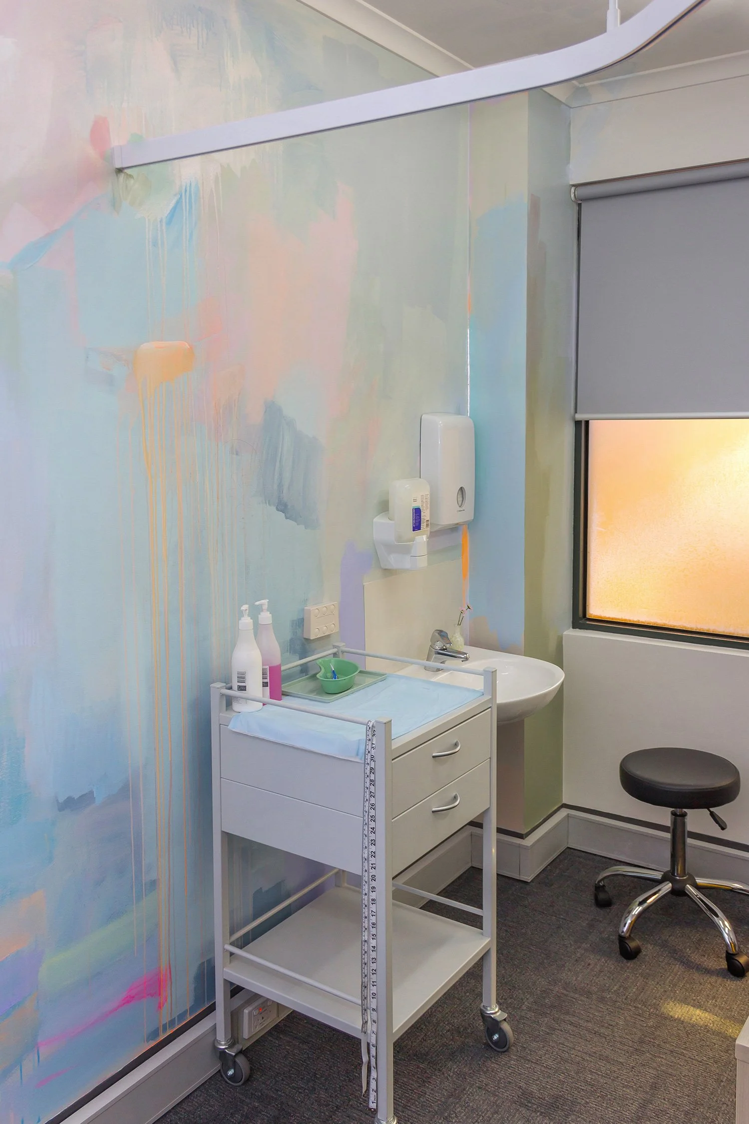 Pastel abstract mural painted in an OB/GYN office, featuring medical equipment and styled furniture.