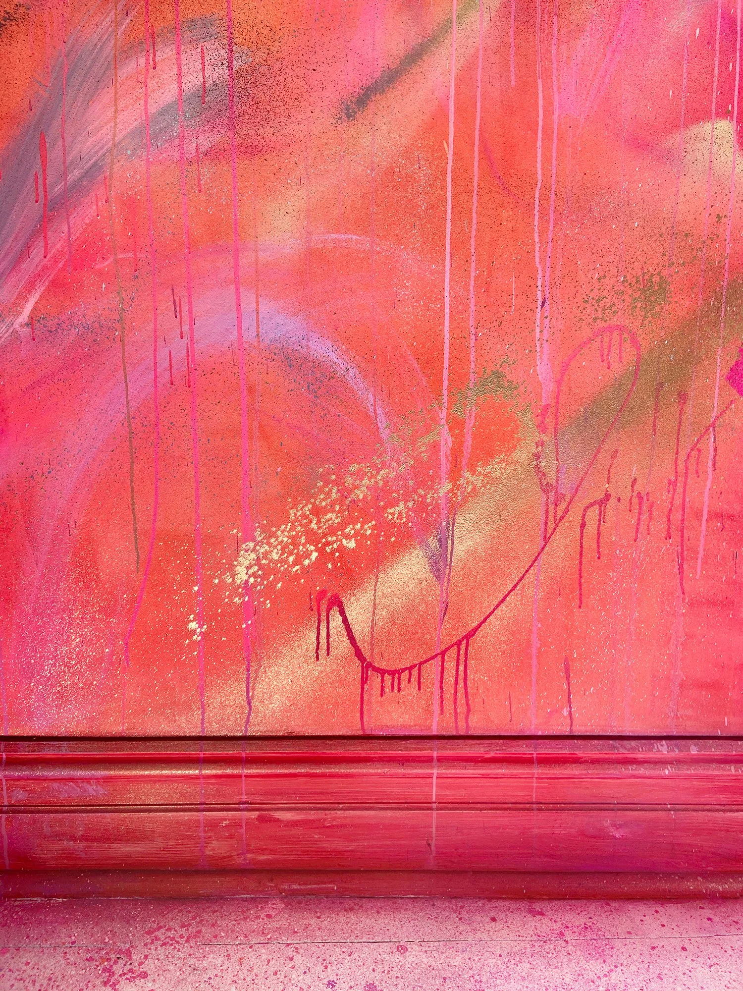 Mural detail showing bright orange painted walls with gold and pink spray painted shapes on top.