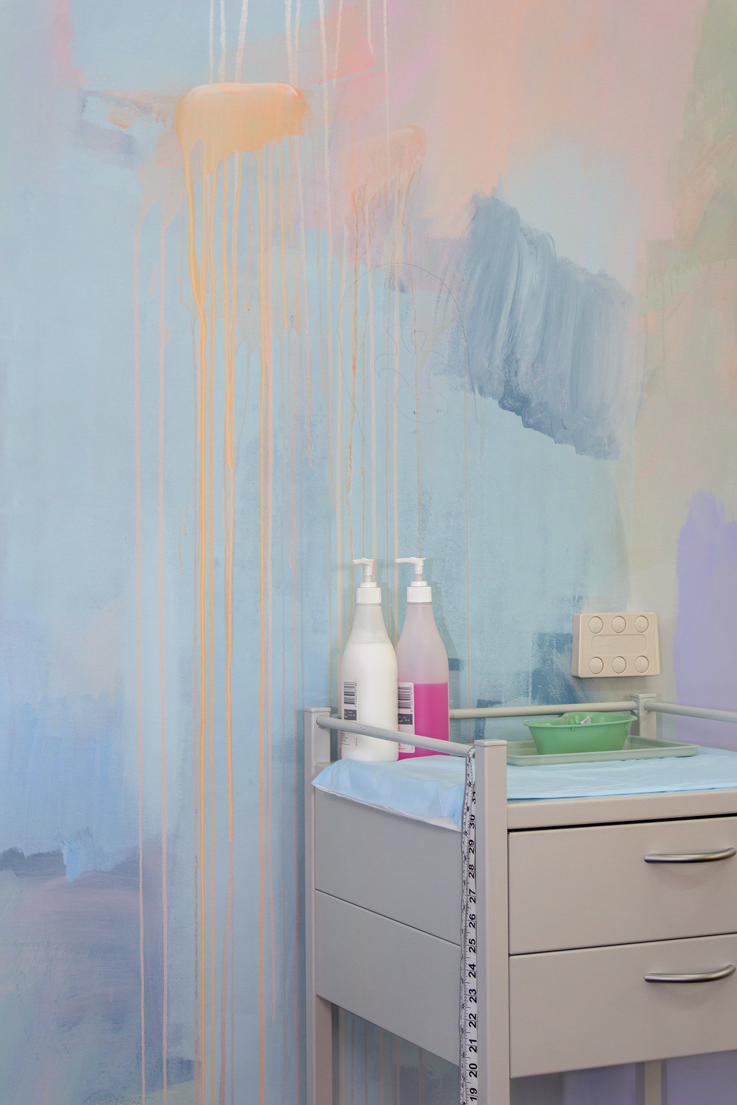 Close up detail of abstract pastel mural featuring dripping paint and medical equipment.