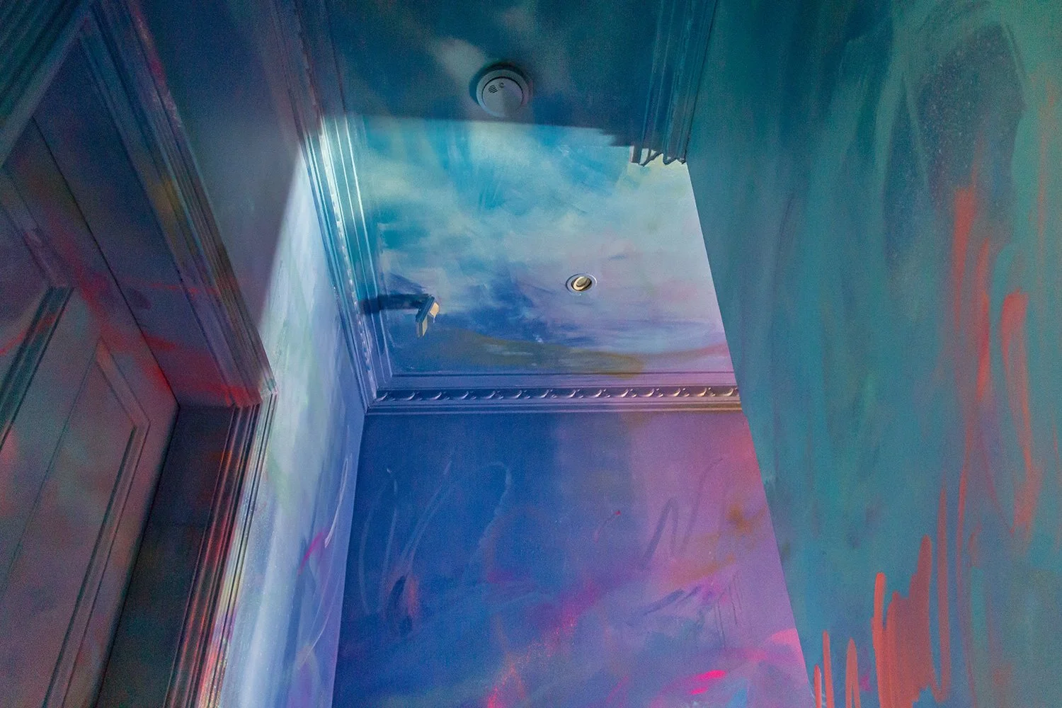 A blue and purple pastel mural, with paint covering the walls and up onto the ceiling. The paint appears like water merging into the sky.