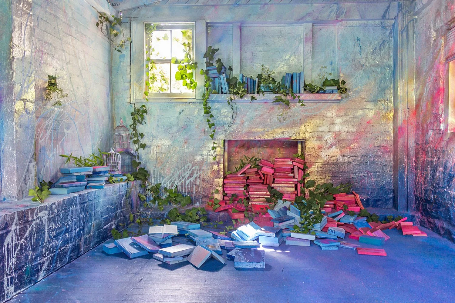 Red and blue books spill out of a painted fireplace, while greenery sprouts up between books. Gold spray painted flames spread out across the walls.