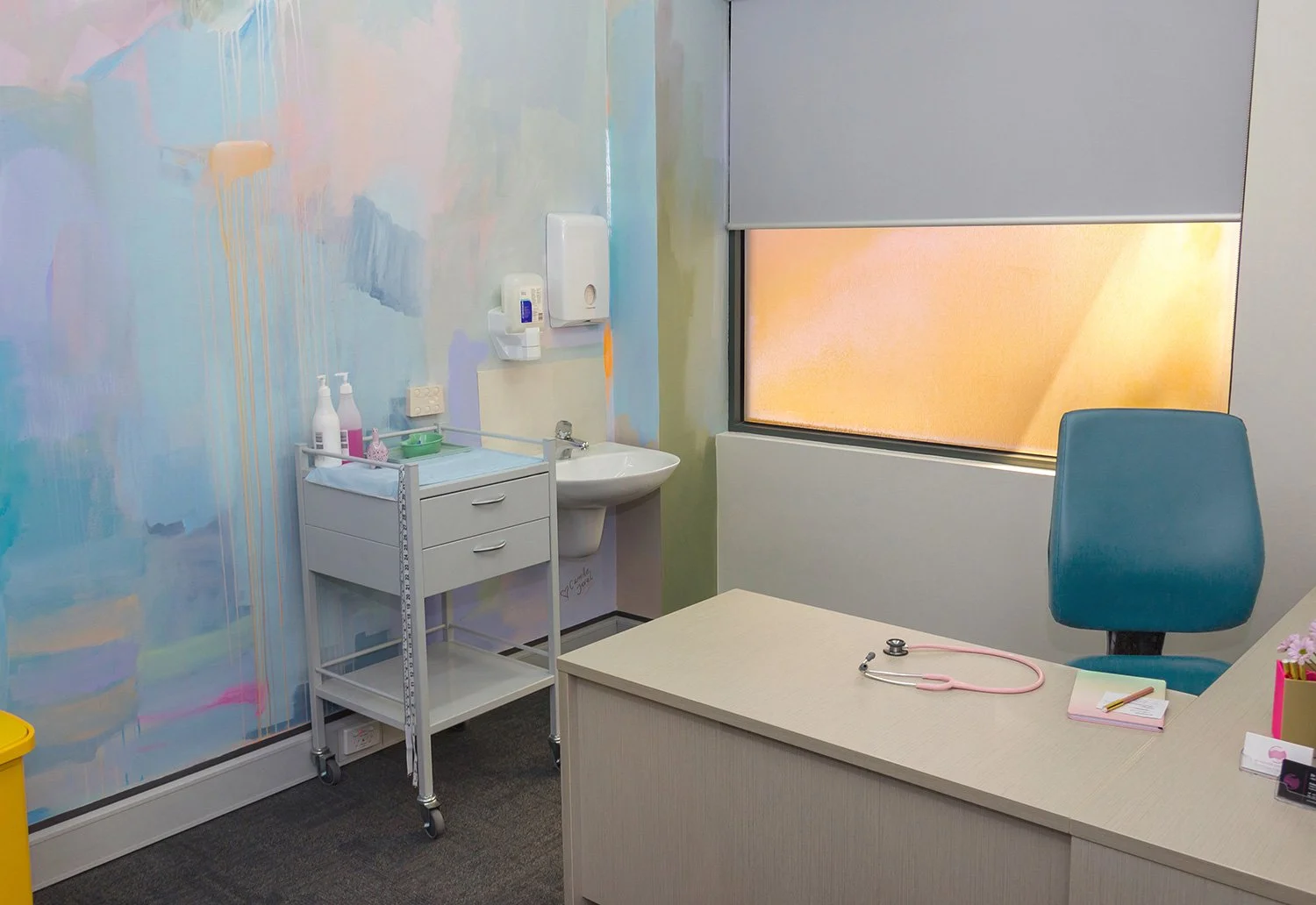 Abstract pastel mural painted in an OB/GYN office, featuring pink stethoscope and desk.