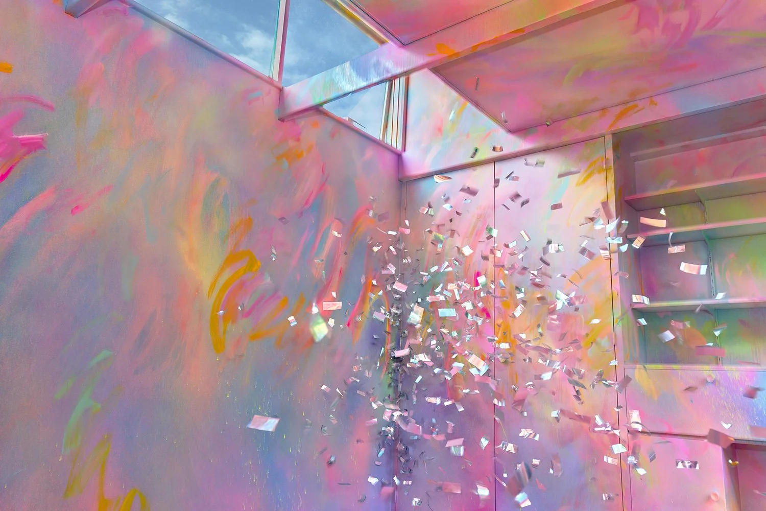Silver metallic confetti explodes in front of a pastel immersive mural exploring the theme: heart.