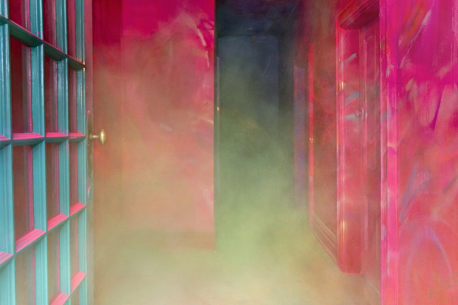 Yellow smoke from a cannon pours out of an artistically painted hallway, the smoke contrasts with the bright red walls.