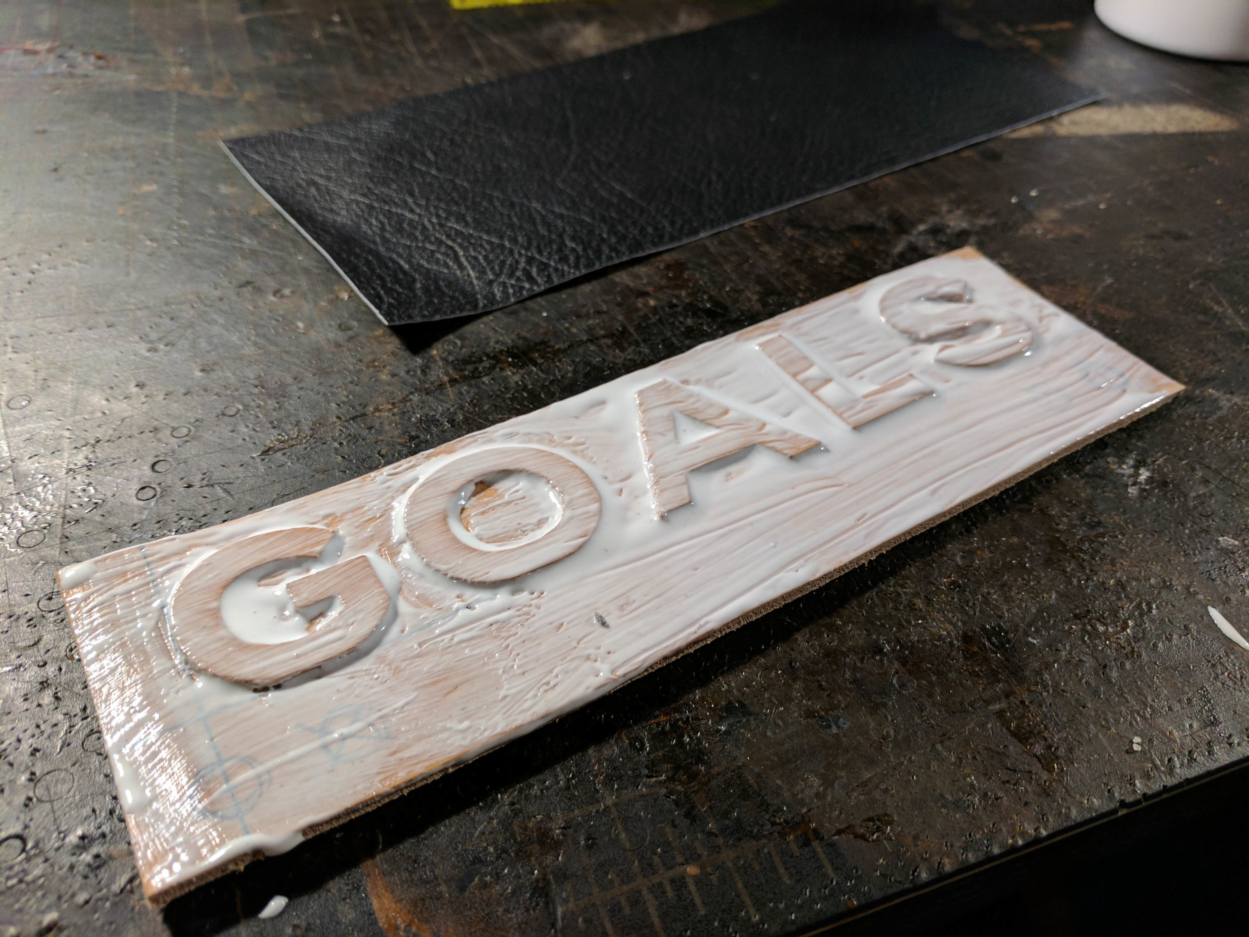 Once the letters were glued on and that glue had dried, I covered the entire project in glue and placed a very thin pig skin on top.