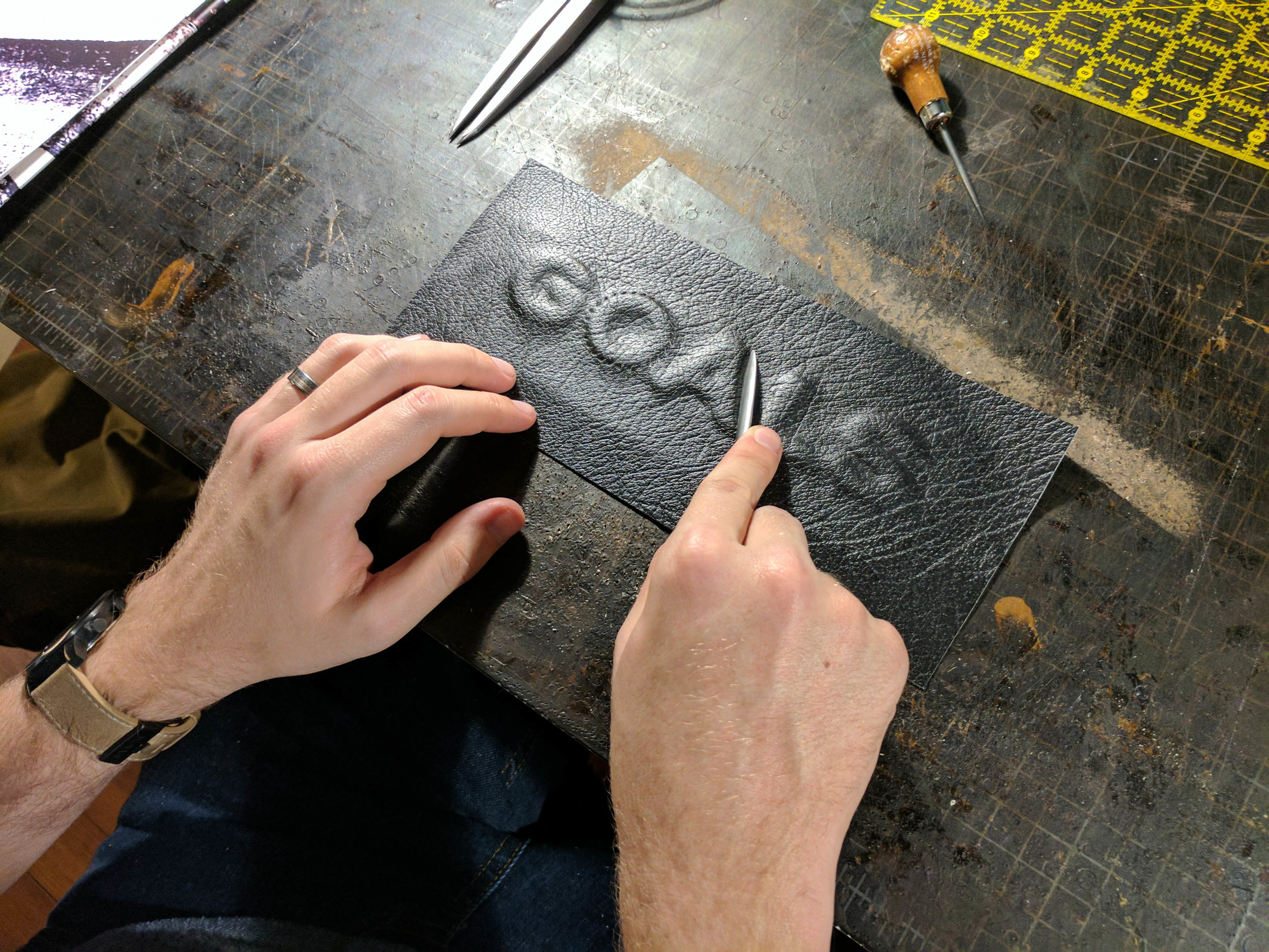 I then formed the leather around the letters using a bone folder and allowed the glue to dry. From there I marked my stitching lines, created the holes, and stitched the project. To finish the project, I trimmed off the excess pig skin and burnished the edges.