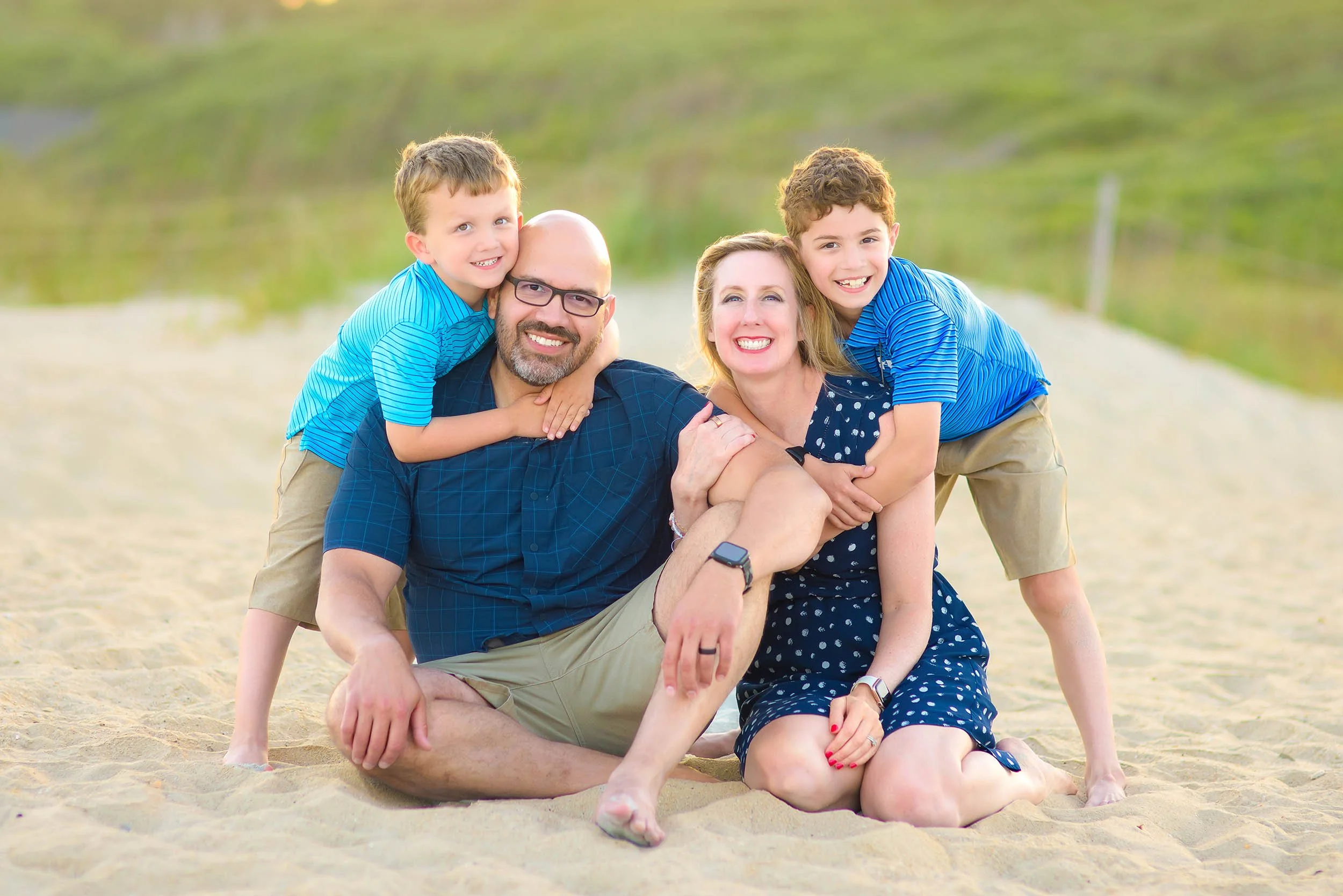Family of four sitting together on the sand during a beach portrait session at Myrtle Beach State Park in South Carolina.