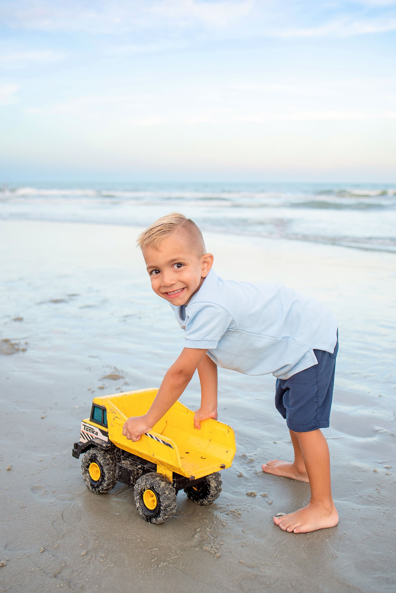 Boy playing with truck on the beach.
