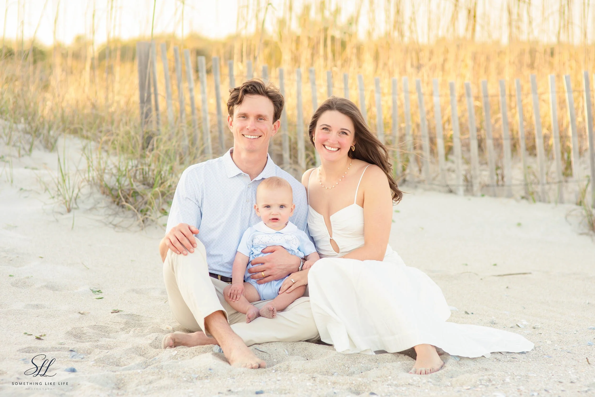 Young family sitting together on the beach with baby during a sunset session in DeBordieu Colony, South Carolina