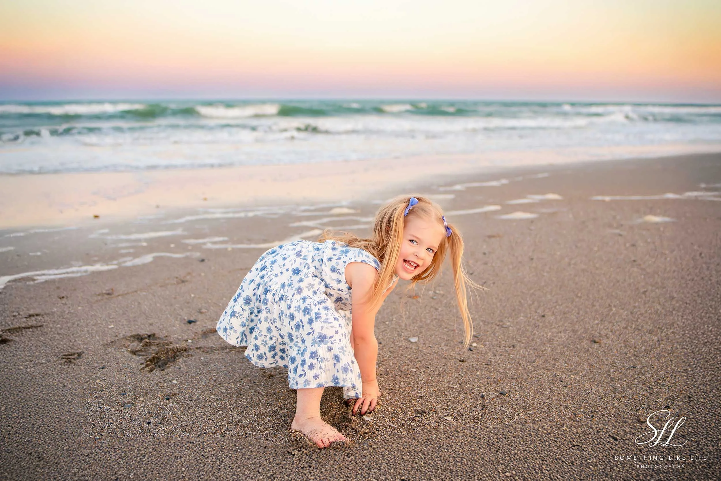 Smiling toddler playing on the beach at sunset during a Myrtle Beach State Park family photography session.