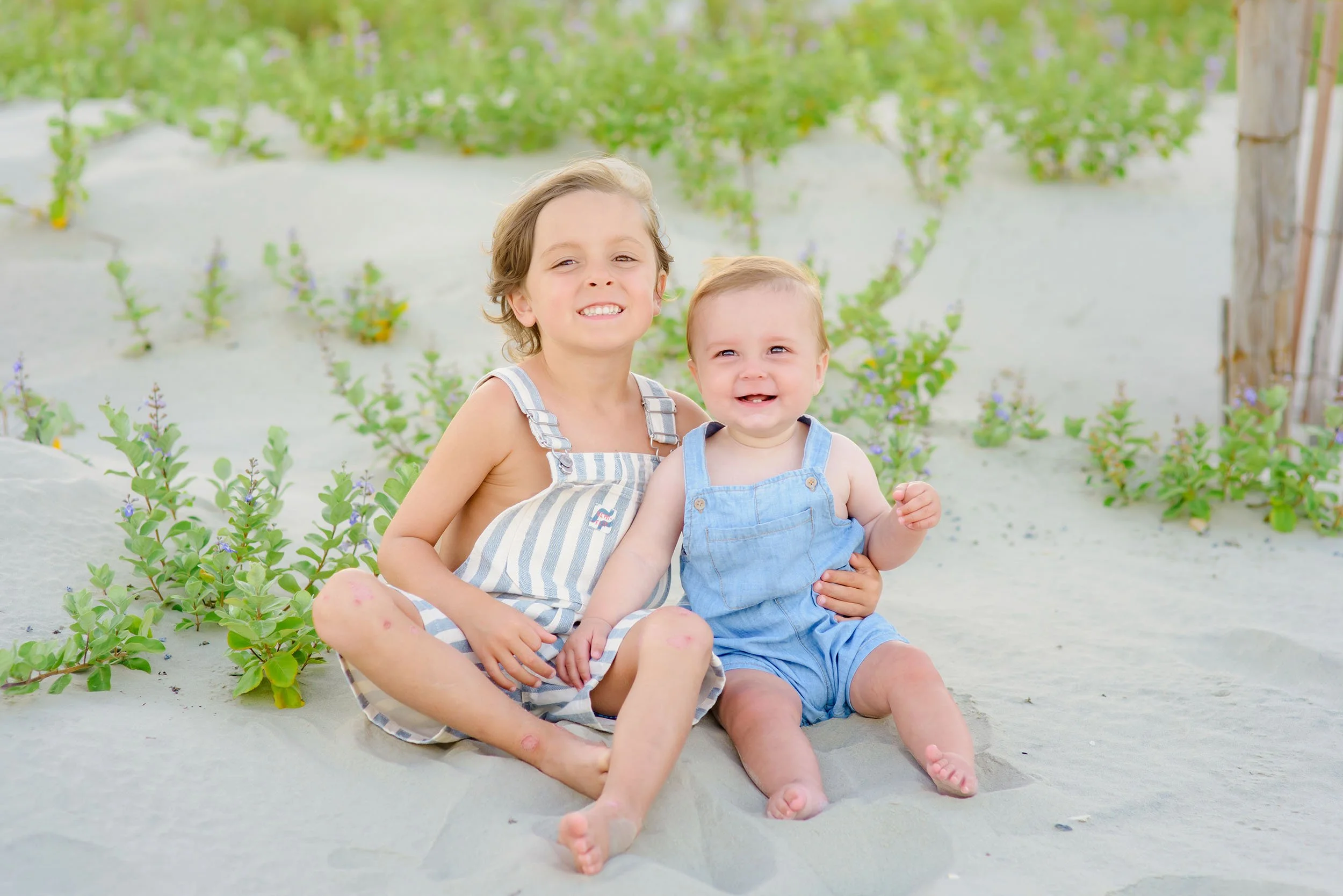 Two sweet young brothers sit smiling in the sand dunes of North Myrtle Beach