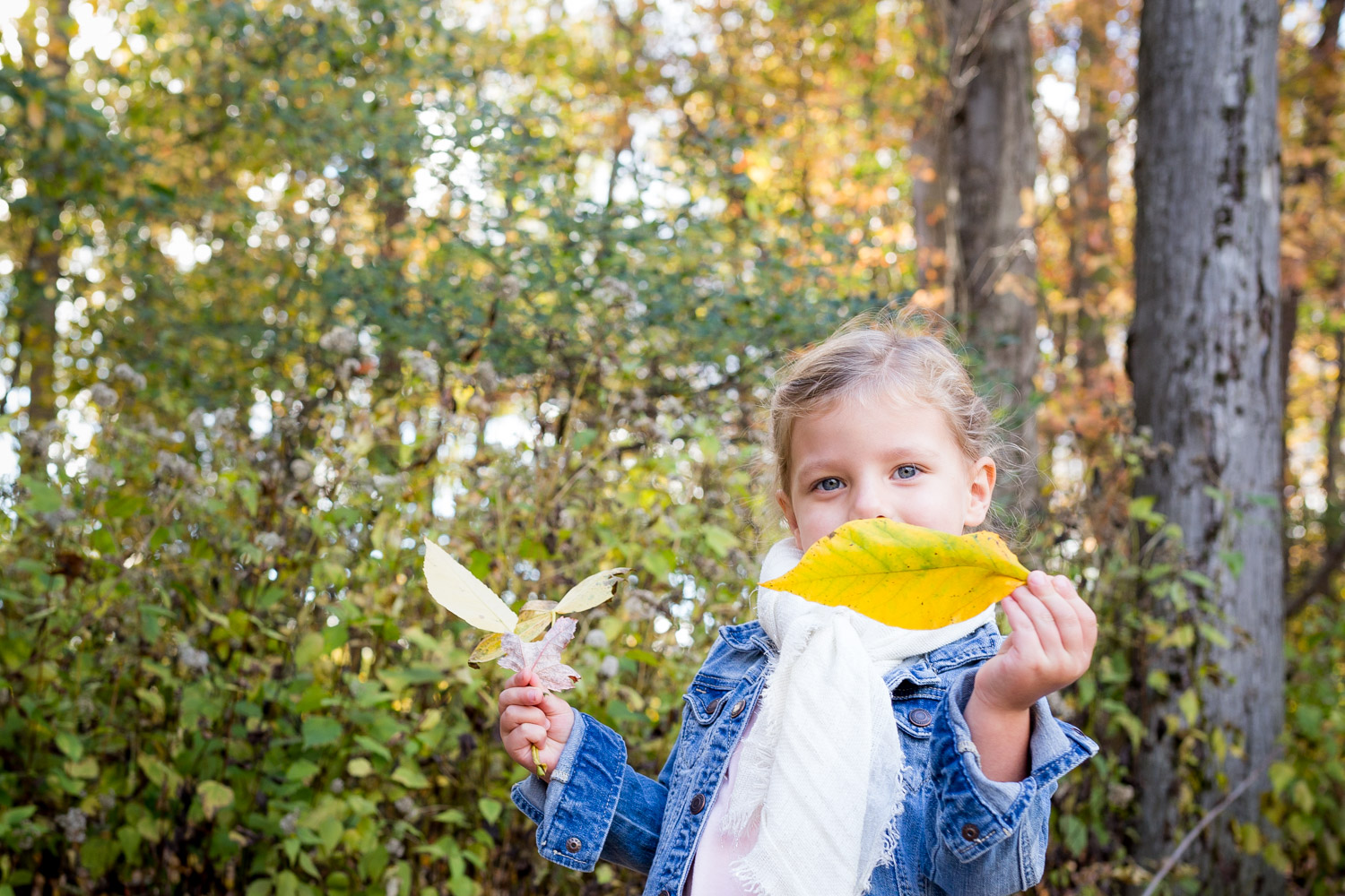 little girl hiding behind a yellow leaf
