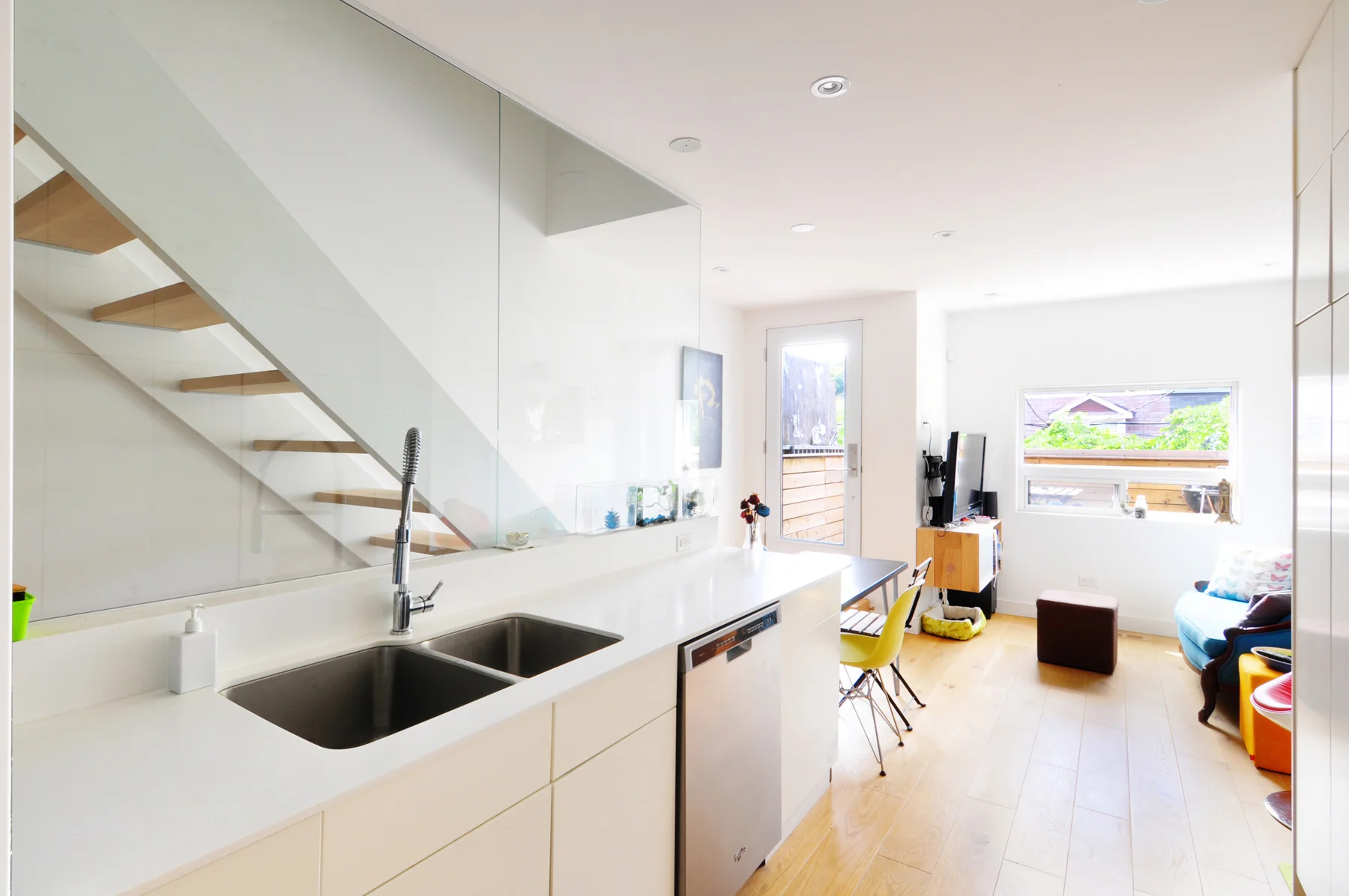A glass wall acts as a barrier between the kitchen and the floating staircase, and serves as a backsplash that allows natural light into the space. 