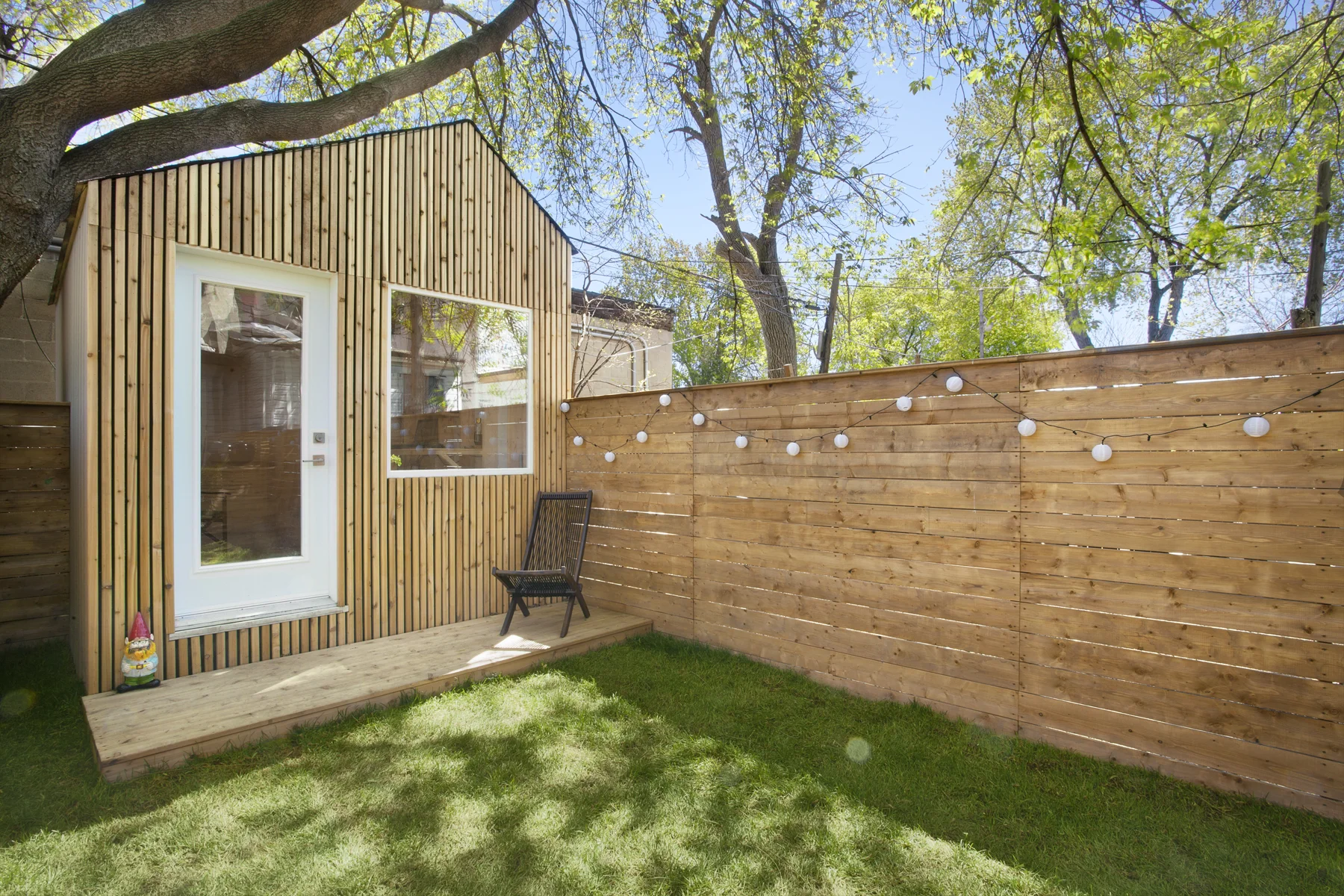 Cedar strips & matching wood boards are used for the decking, fencing and studio cladding to create a unified space to frame the well-grown trees and green lawn