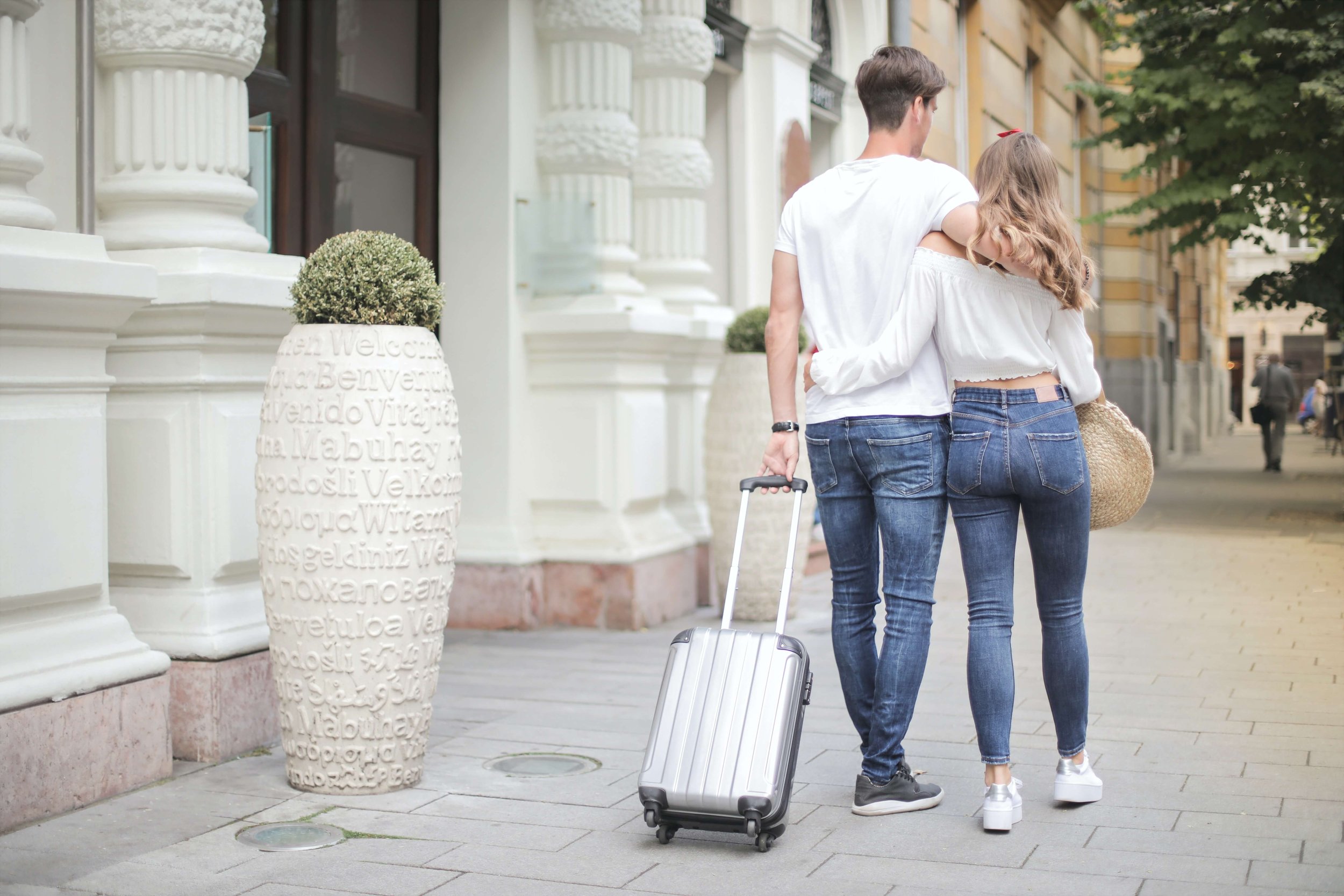 A couple walks together with their luggage on a city street during vacation. Comparing your experiences to Instagram Reality can be detrimental to your mental health. Therapy for Young Adults in NYC can offer support and guidance.