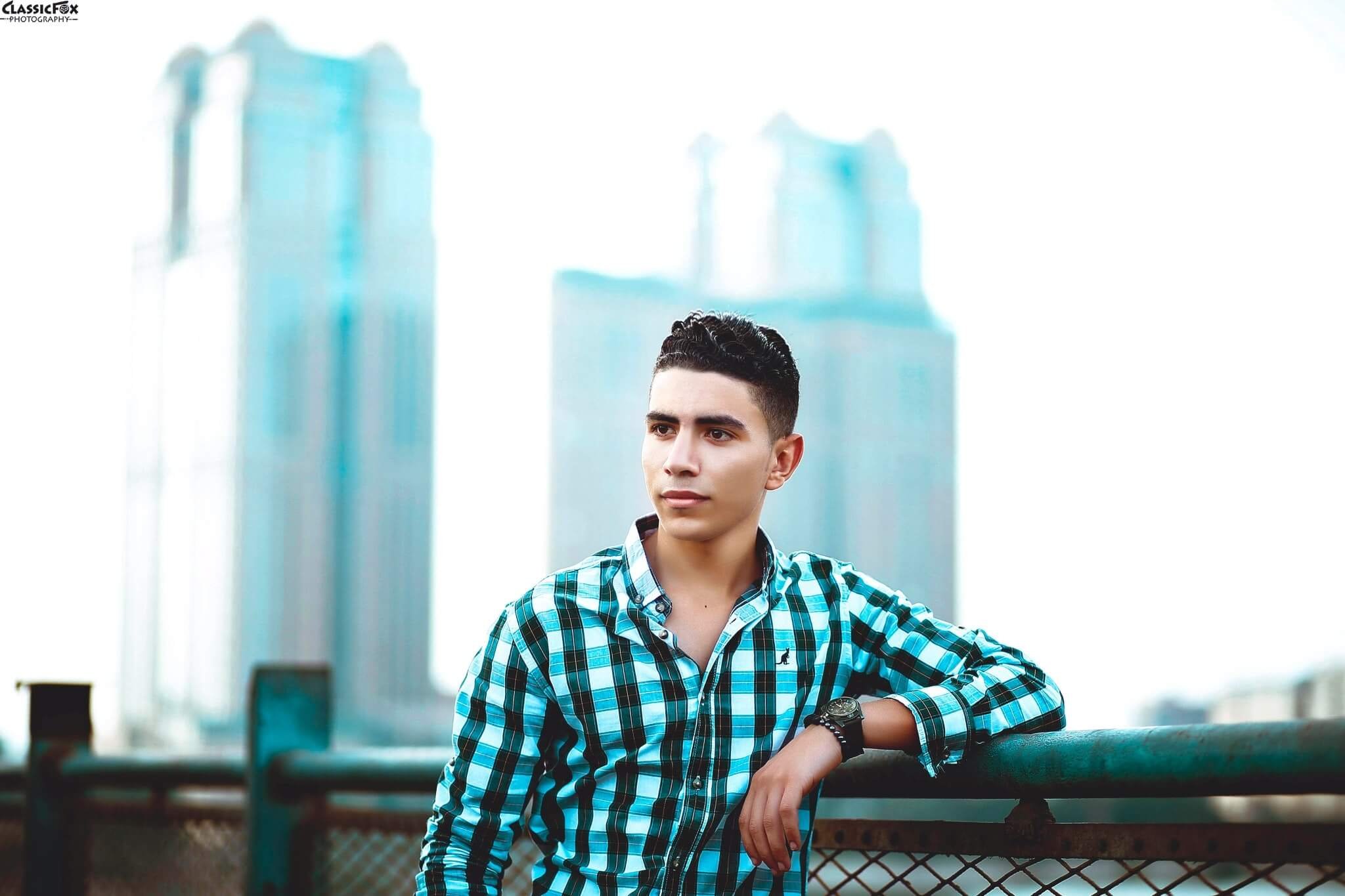 A young man stands with his arm on a fence overlooking the city as he contemplates the transition to adulthood. Therapy for Life Transitions in NYC can help you develop a plan of action for your future.