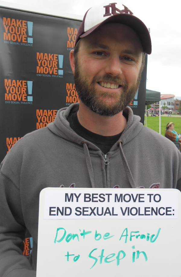 A man holds a whiteboard that says “My best move to end sexual violence: Don't be afraid to step in.”