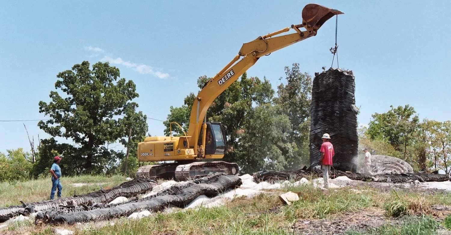 Yellow excavator lifting a blasting mat monitored by drilling contractors and blasting contractors insured by Nobel.jpg