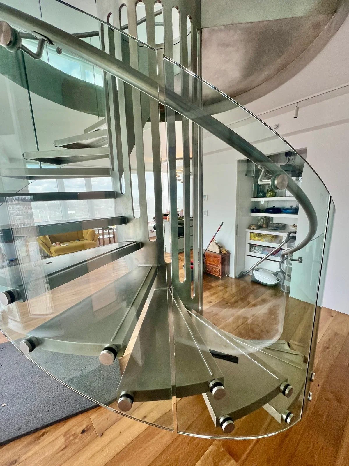 Sculptural metal spiral staircase with floating treads and glass guardrail