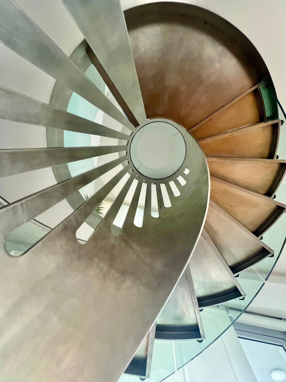Custom spiral staircase with curved glass railing in a luxury NYC duplex