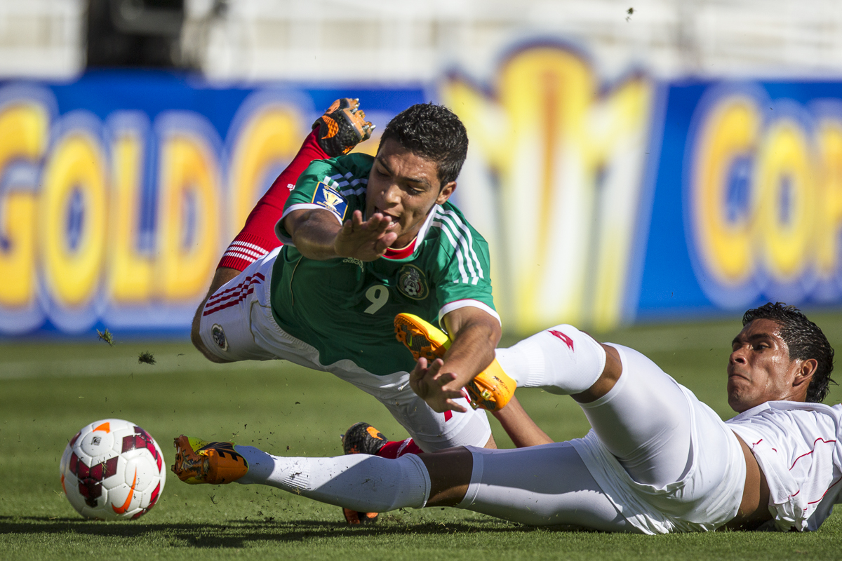 Carlos Rodriguez of Panama (White) slides in hard against Raul Jimenez of Mexico (Green) during the second match of the 2013 CONCACAF Gold Cup between Mexico and Panama at the Rose Bowl, Pasadena, Calif., on Sunday, July 7, 2013. Mexico would go on to lose this match 2-1. (© Fernando J Tirado 2013)
