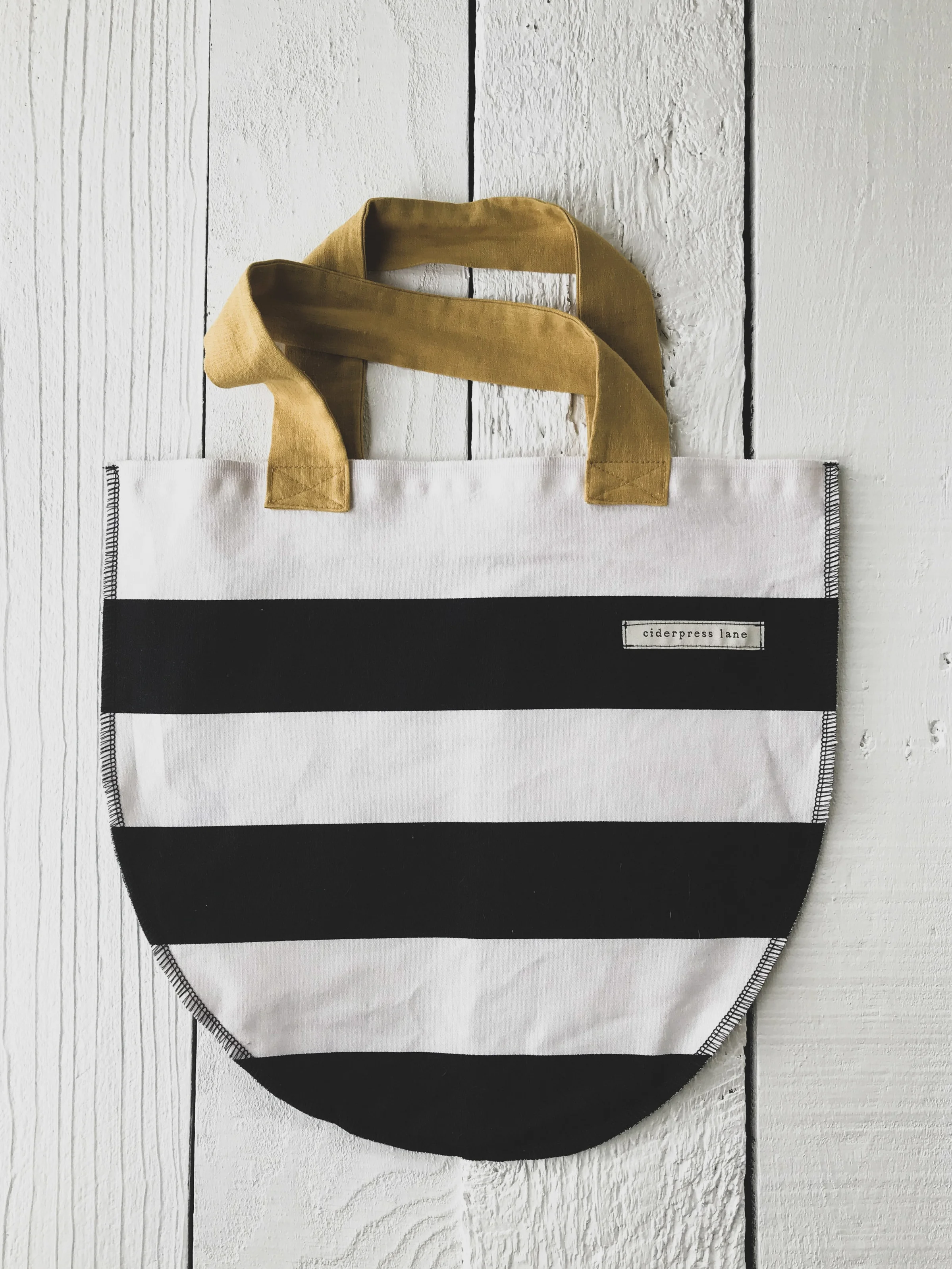 CiderPress Lane Tote is the perfect classic black and white stripe with a pop of mustard yellow. Sure to go with everything! Best part, with every purchase 10% gives back to fight human trafficking.