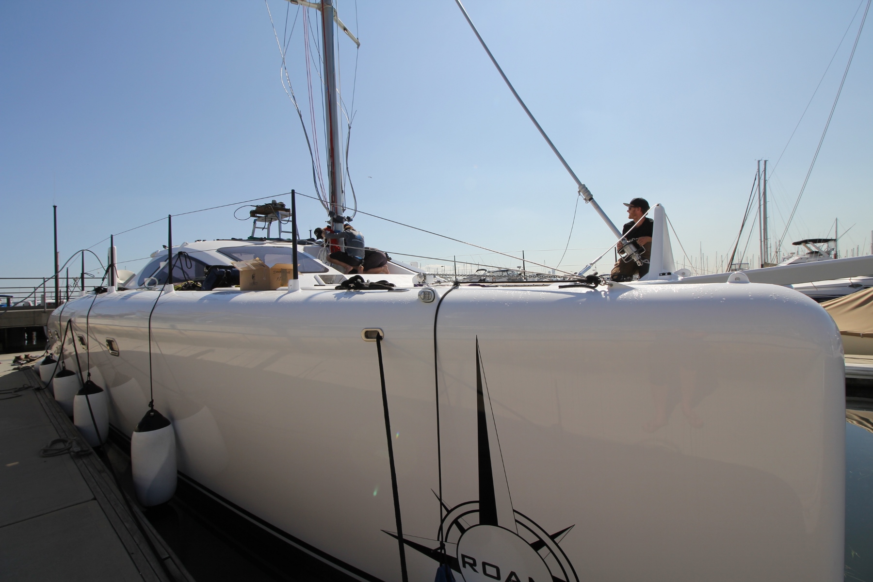 Set down. The mast is landed out on the step and the forestay is pinned off. Halyards are then used to tie back and align the rig while the shrouds are measured and terminated. The crane is left connected as a safety until the cap shrouds are pinned off and tensioned. 