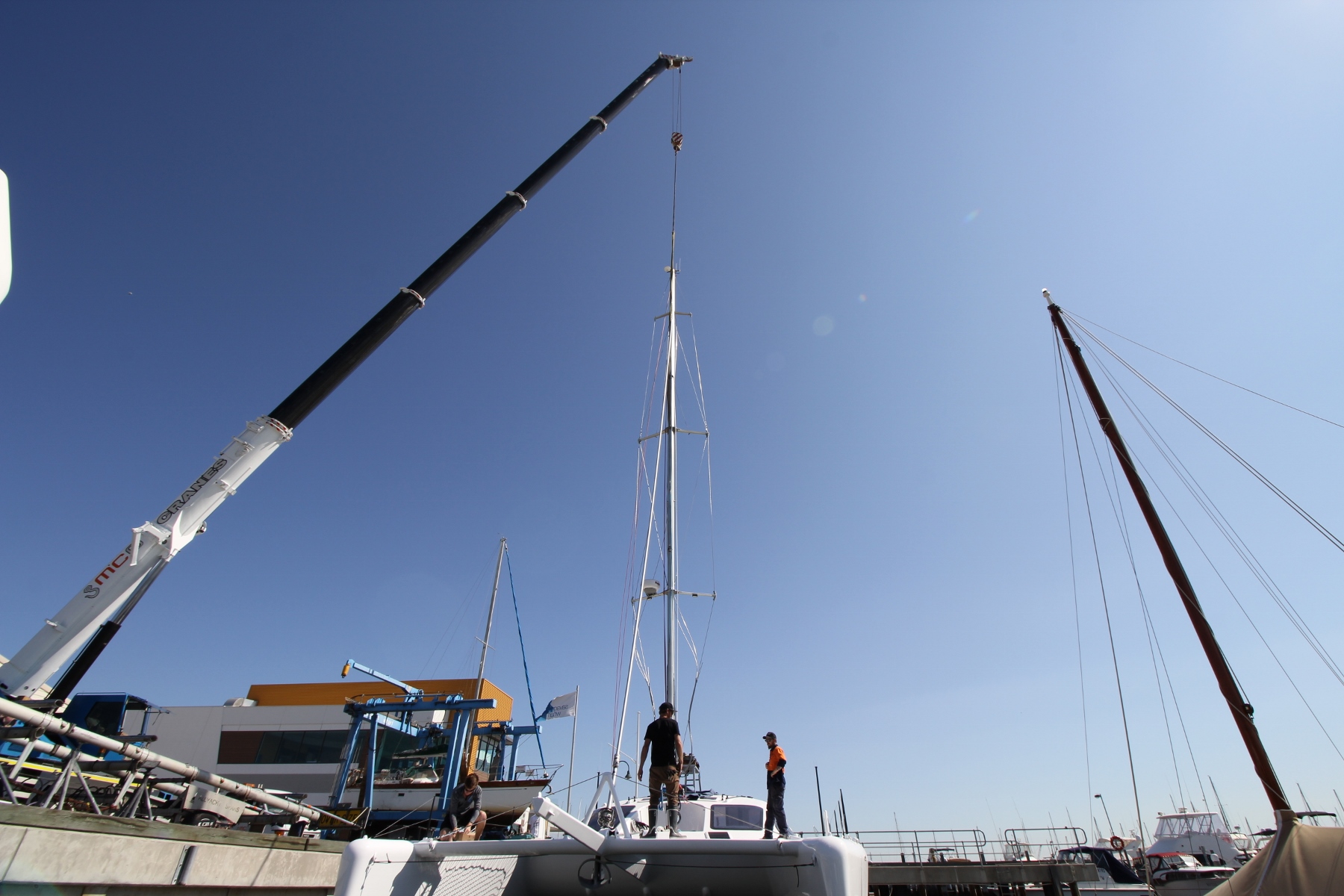Michael on the fore deck as the crane lowers the mast onto Roam .