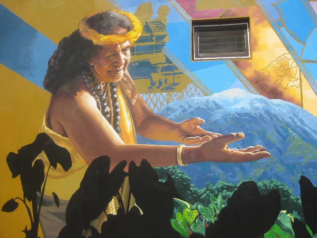 The mural is an anachronism, featuring a pre contact Iao Valley and its surroundings with a mixture of figures from the past and modern day. One figure sits in field of Taro plants which exist in the place of Maui’s sugar plantation, next to the restored flowing river.