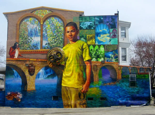 This Mural's design took its inspiration from a summers worth of neighborhood programs involving writing, painting, and mask making, and is very loosely inspired by the Paul Lawrence Dunbar poem “We Wear the Mask”. 